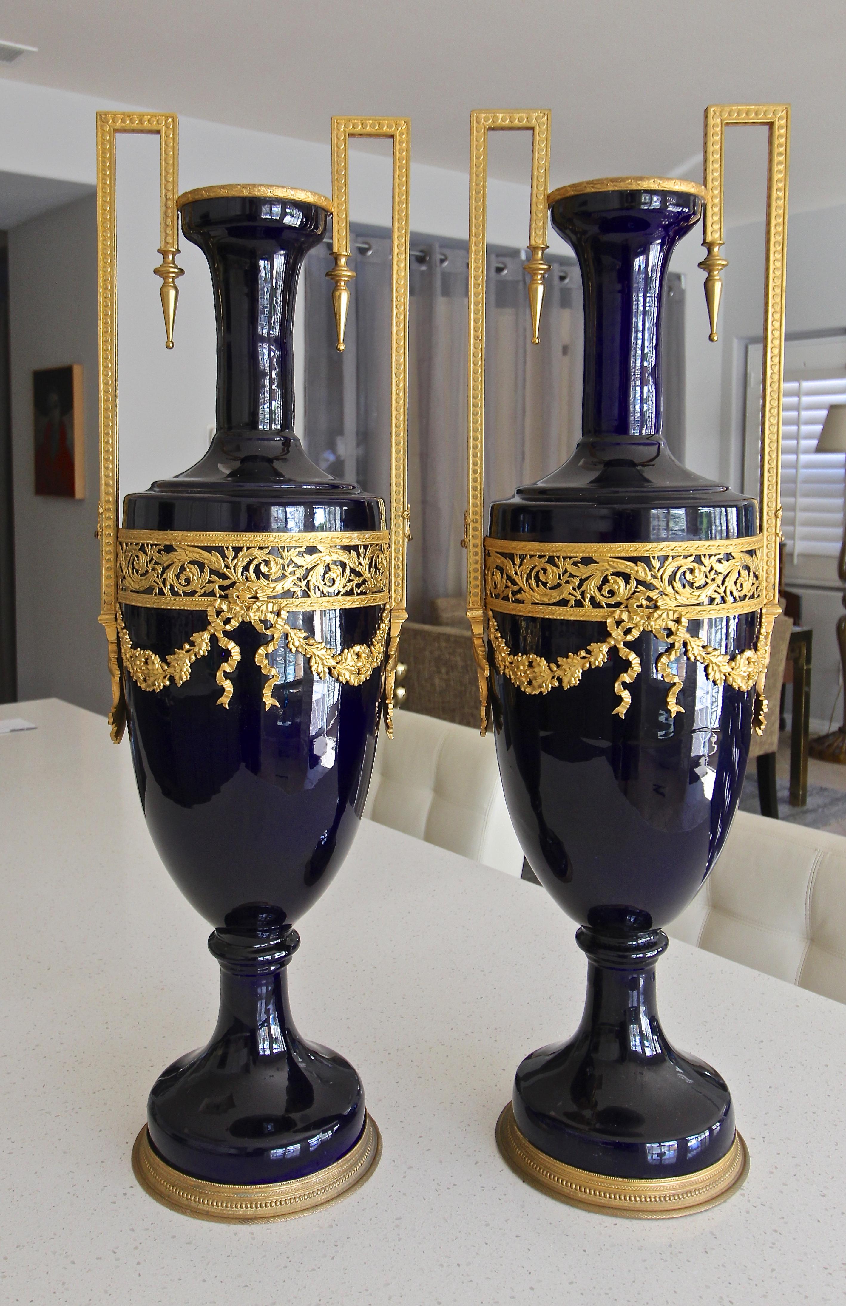 A pair of French porcelain cobalt blue bronze ormolu-mounted urns or vases. Nicely chased details to bronze mounts.
(See condition comments).