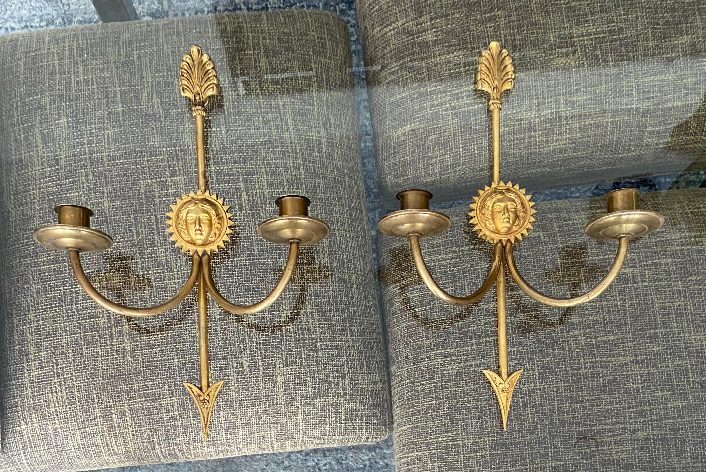 Pair of 1920s French Empire style brass 2 arm candle sconces with arrow and sun face motif. Not electrified.