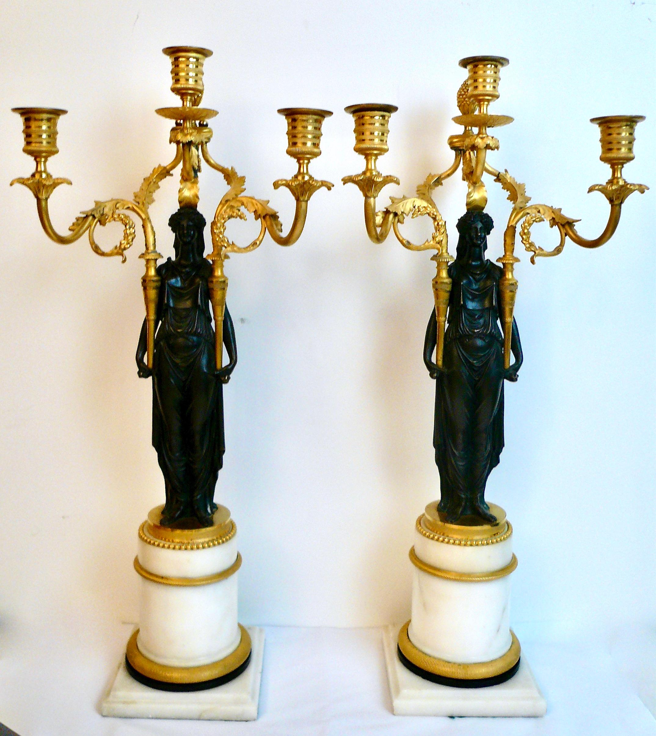 This amazing pair of Louis XVI / Directoire period candelabra are of the finest quality.
The figures are modeled as Roman Vestal Virgins issuing three scrolling acanthus leaf candle branches. They are mounted on Carrara marble colunmnar bases with