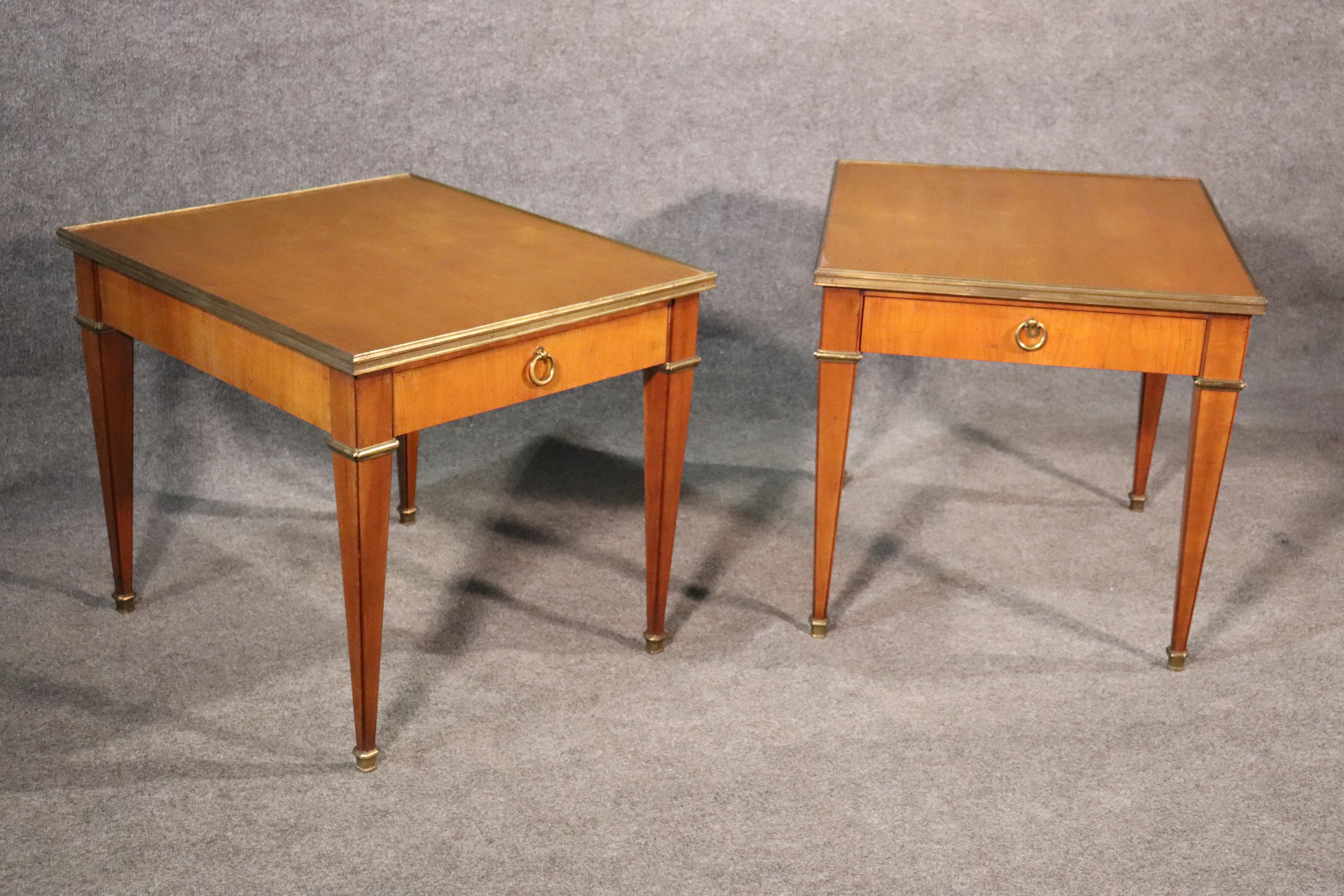 This is a classic pair of sophisticated and yet simple French Directoire style end tables by Baker Furniture company. They are in very good condition and made of cherry with bright brass ormolu and pulls. They are dovetailed and of the highest