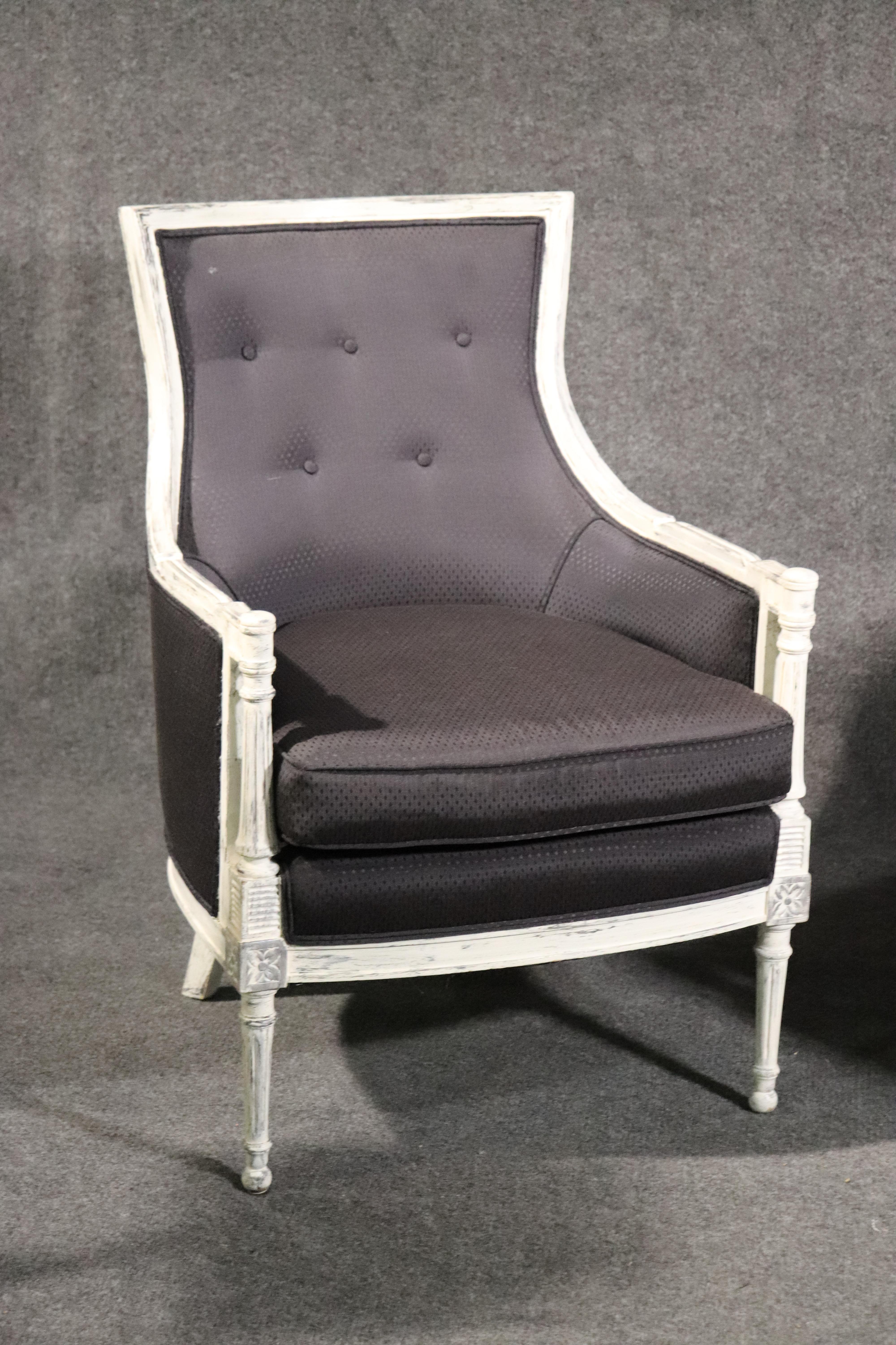 This is a fantastic pair of French style bergère chairs in good black upholstery and bright white distressed painted finish. The chairs are very comfortable and go with everything in your home. They date to the 1950s era and have been recently