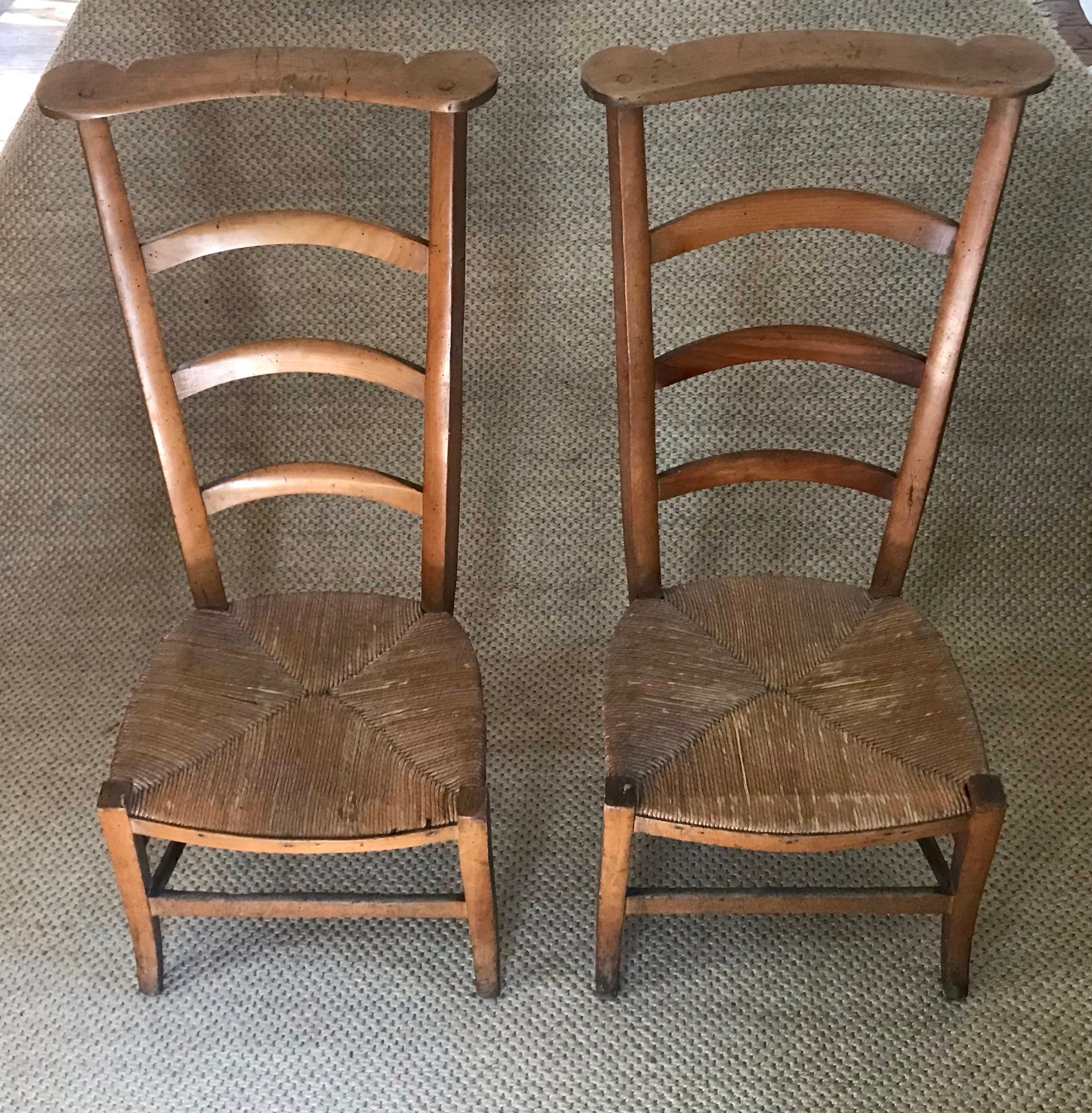 Pair French dressing chairs. Pair vintage French provincial chairs with shaped top rail, ladder back and low rush seat for putting on your boots in the morning at your French chateau and slinging your jacket over the back of the chair. Dior would’ve