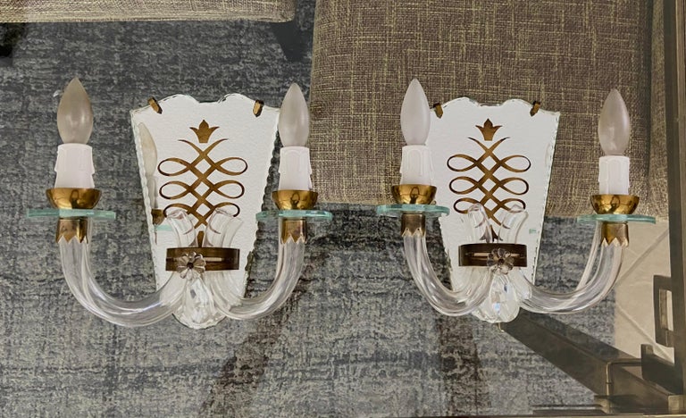 Pair of two-arm brass French 1940s mirrored eglomise etched wall sconces. Nice detailing including cut scalloped mirrored edges. Each sconce uses two candelabra base bulbs. Newly wired. Affixes to wall using wall hook.