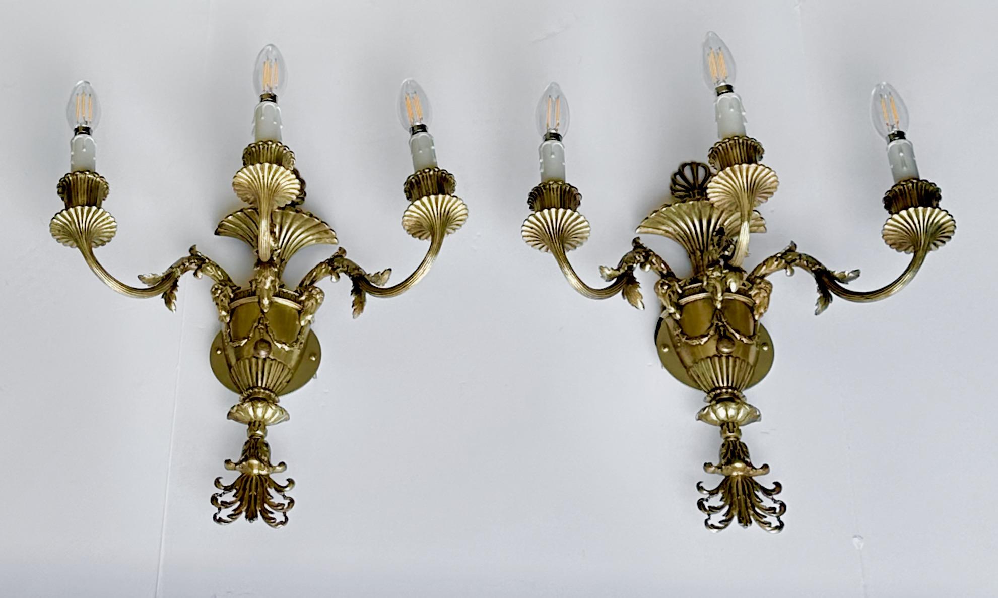 Pair of nicely detailed French Empire style three-arm  brass wall sconces with rams head motif and other design elements characteristic of French aesthetics. Newly wired for US with back plates added for US installation. 