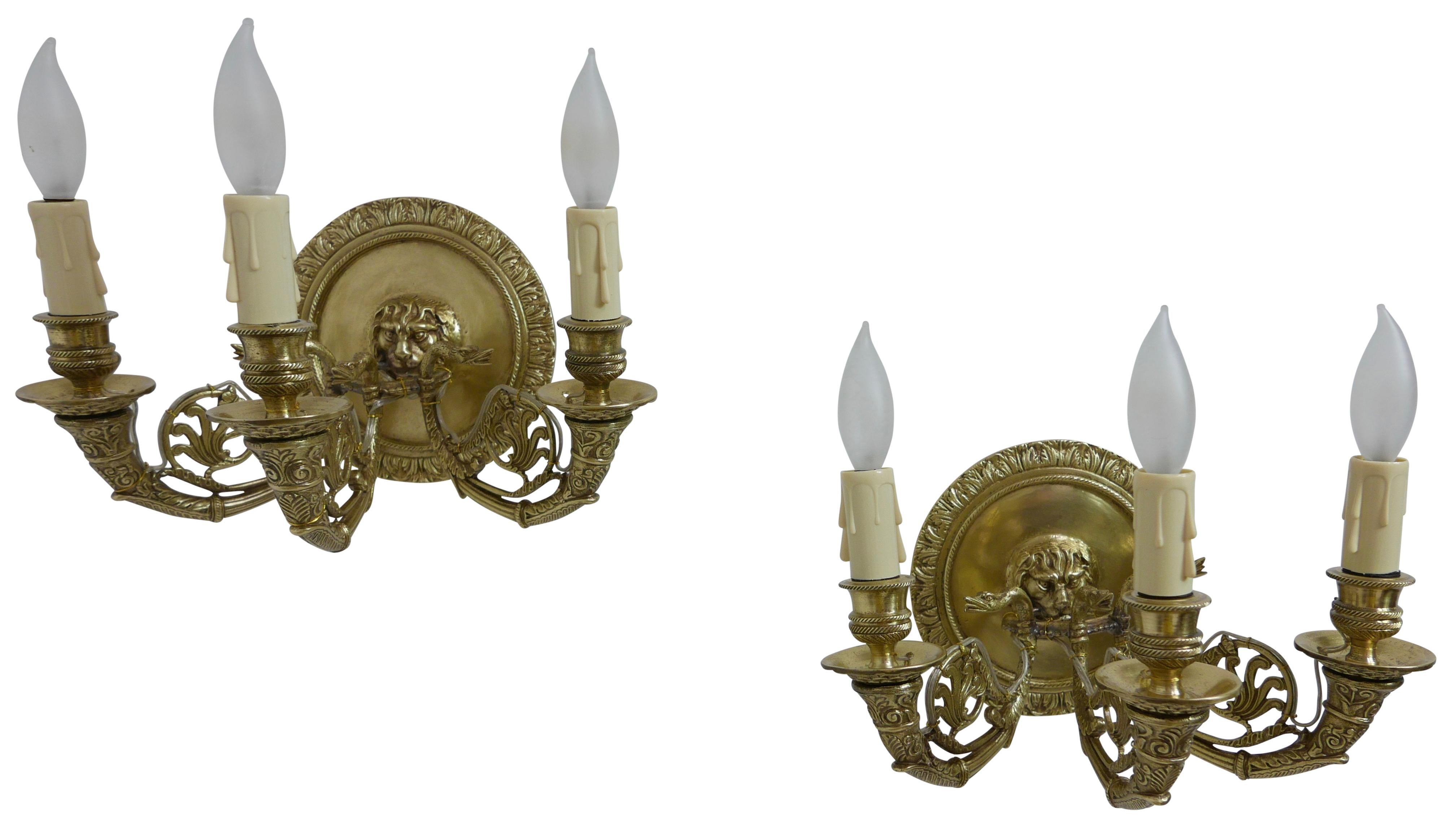 A pair of French Empire three-light brass sconces with lion faces, converted to electric.
Recently restored, having wax candle sleeves and holding chandelier size light bulbs.
France, early 19th century.
 