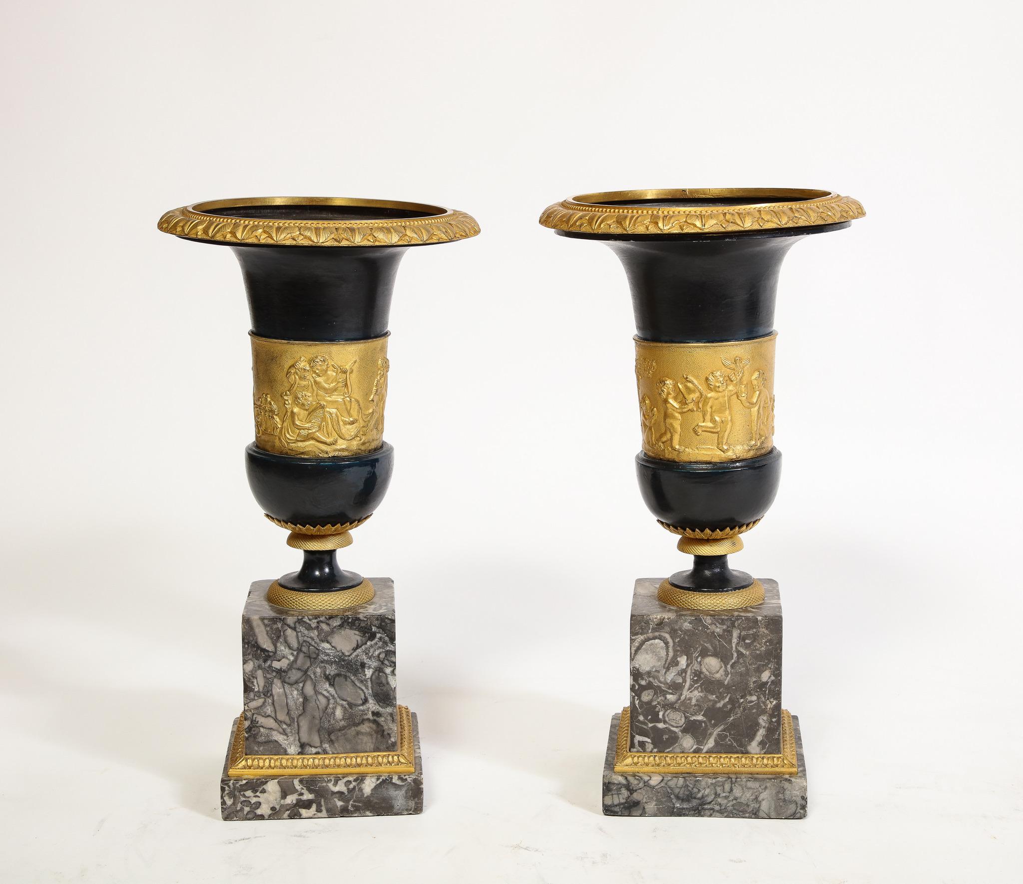 Ein Paar französischer Vasen in Medici-Form aus patinierter Bronze und Ormolu auf Sockeln aus grauem Marmor, mit neoklassischen Puttenmotiven. Das Vasenpaar ist in der Medici-Form konstruiert, mit aufgeweiteten Rändern, zylindrischen Körpern und
