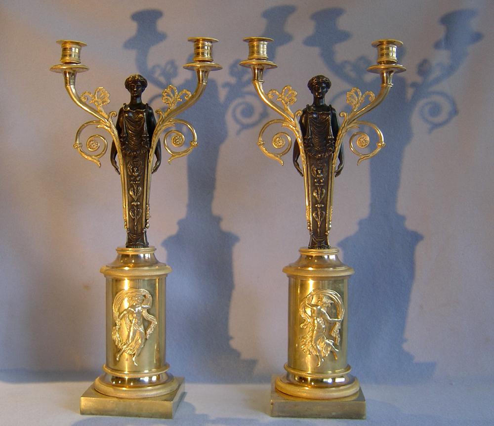 A fine pair of French Empire patinated bronze and ormolu figural two branch candelabra. Set on square ormolu socle with cylinder ormolu stem with applied and paired ormolu mounts of a young woman dancing with a flowing drape. The patinated bronze