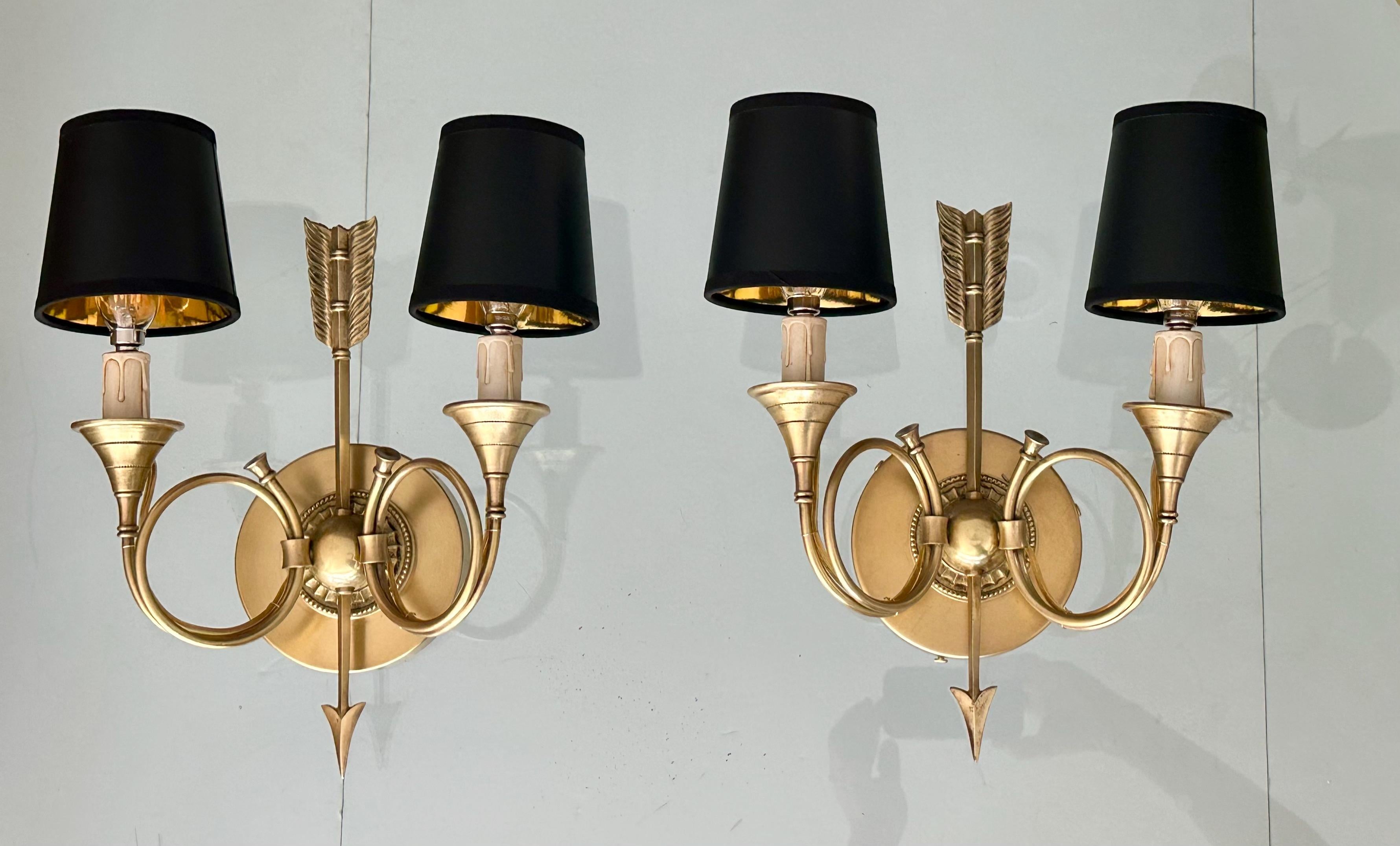 Paire d'appliques murales anciennes de style Empire en laiton à motif de cornes et de flèches. Chaque lampe est composée de 2 lampes de type candélabre avec des abat-jours noirs et dorés. Nouvellement câblée, elle est complétée par des plaques