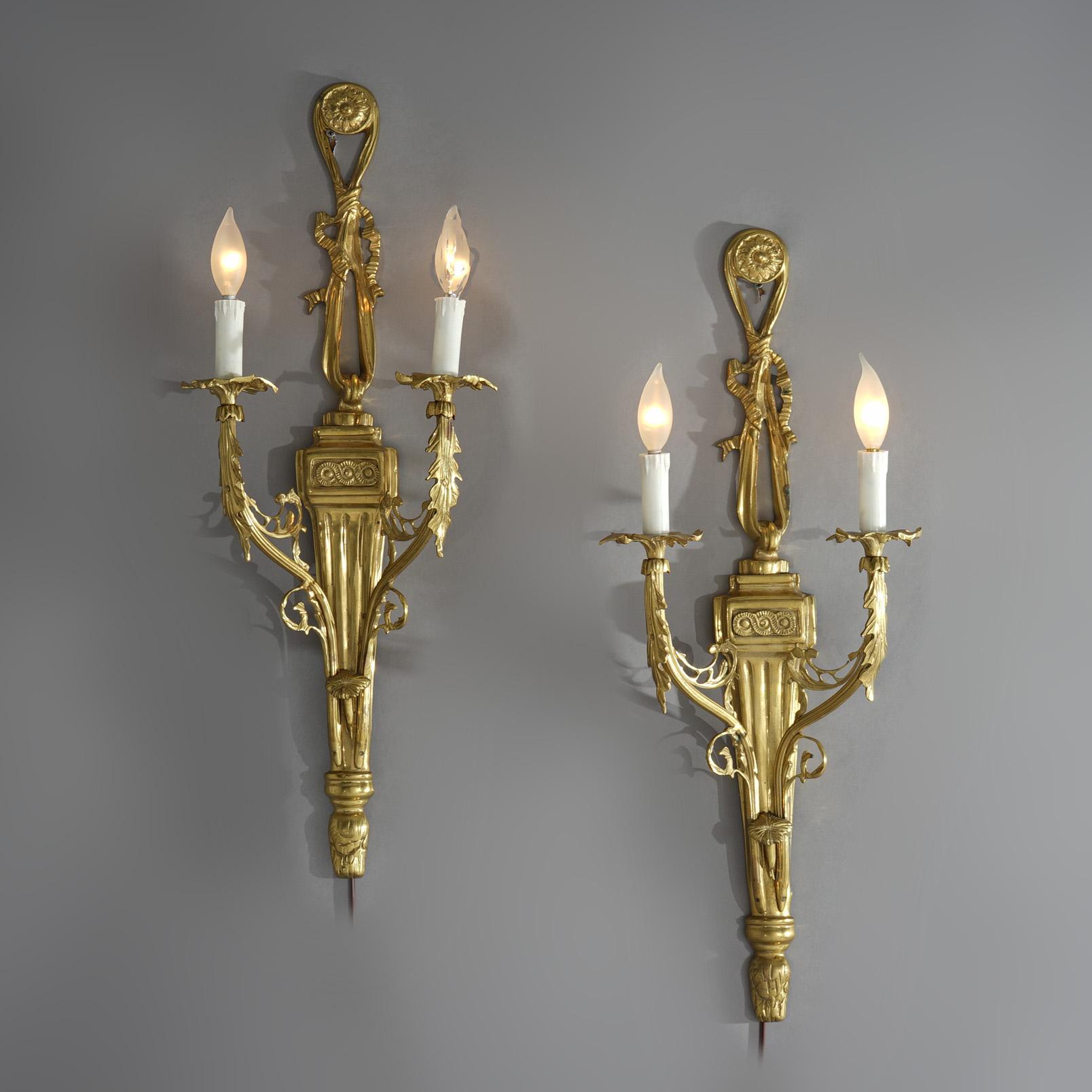 ***Ask About Discounted In-House Shipping***
A pair of French Empire style wall sconces offer cast gilt bronze frames in stylized torchiere form and having foliate elements with two scroll form arms terminating in candle lights, electric, 20th