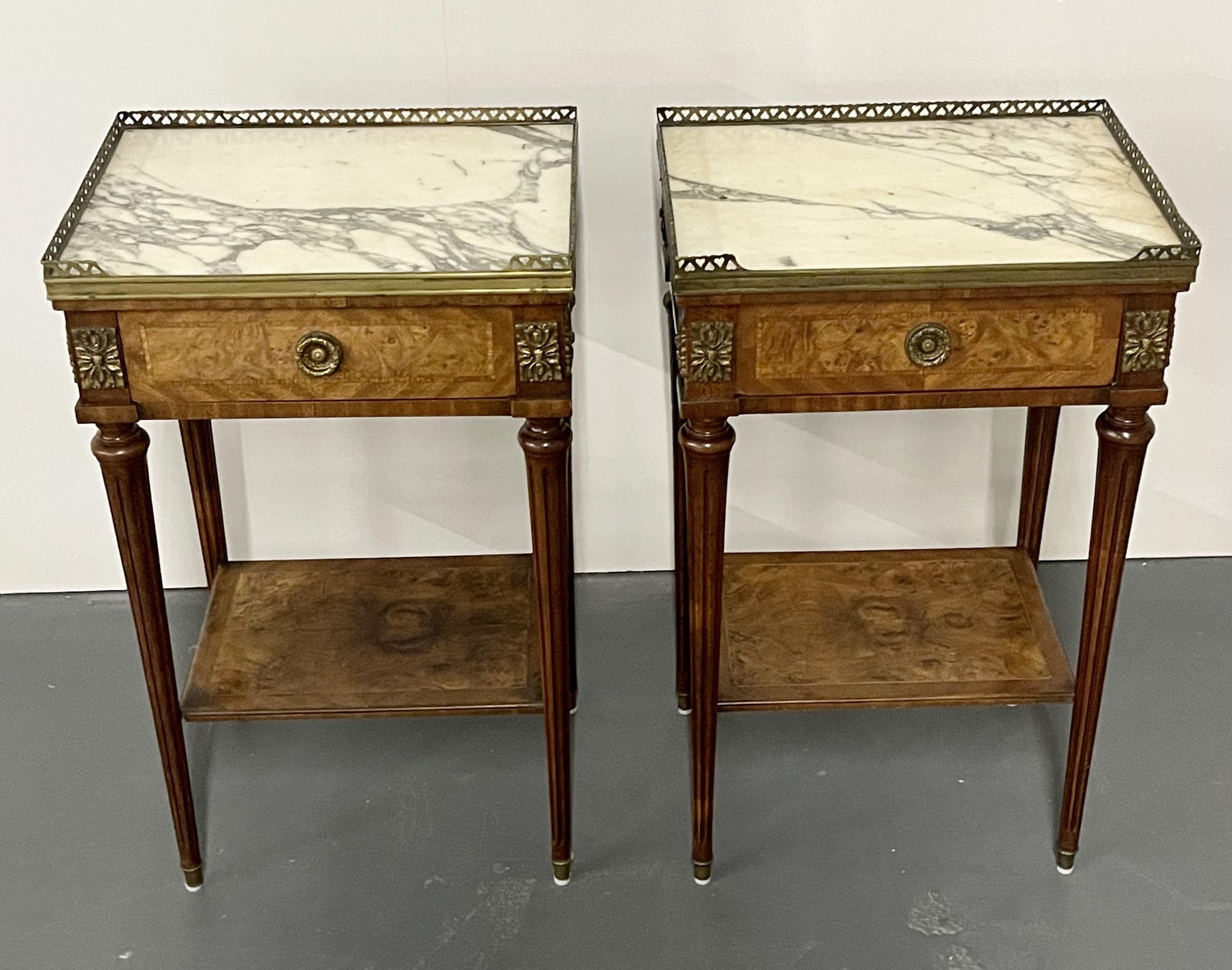 A Pair of French end, lamp or side tables. Each in the Louis XVI Style having a single drawer under a marble top with a bronze pierced gallery. The top supported by long sleek tapering legs with a lower shelf.

Several photographs shot directly