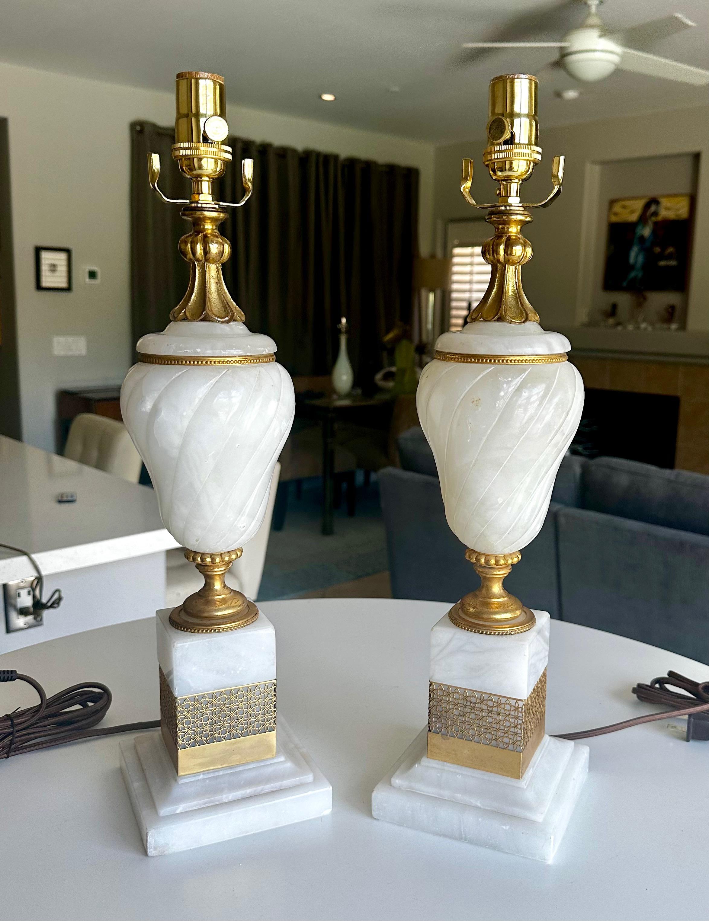 Paire de lampes de table en albâtre de style néo-classique français avec des ornements en bronze doré ou en laiton. L'installation électrique a été refaite à neuf avec des prises à 3 voies et des cordons en rayonne. Il mesure 20