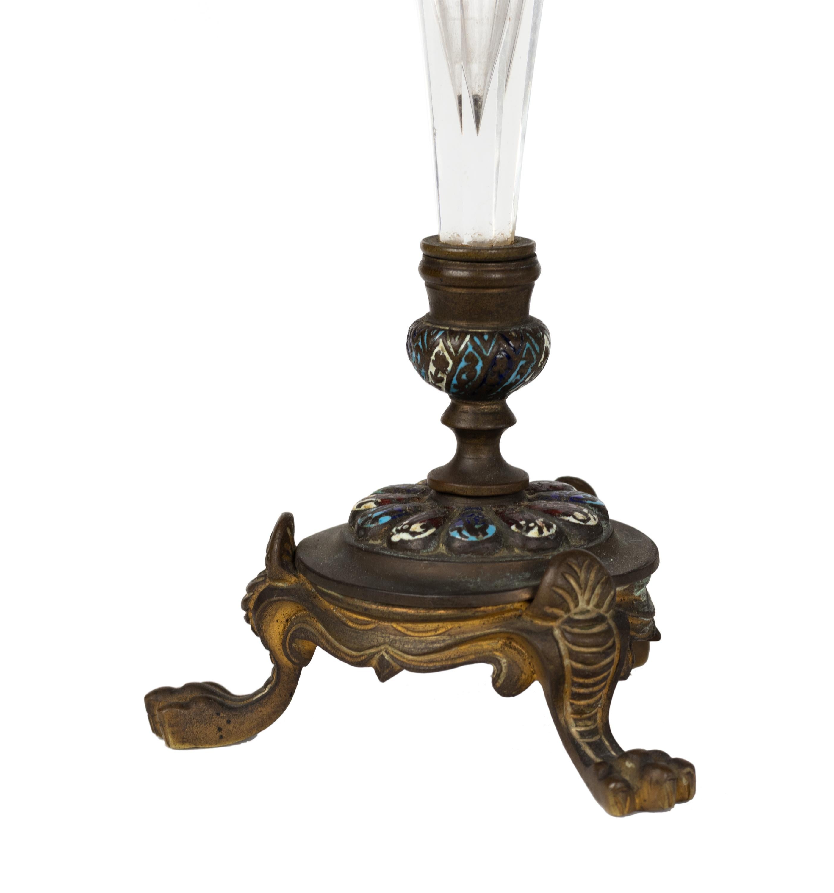 This pair of French trumpet-form vases dates from the late 19th century and blends two luxurious materials: engraved clear glass and richly decorated gilt bronze mounts with champlevé enamel detailing. 

The elegant trumpet-shaped glass tops rest