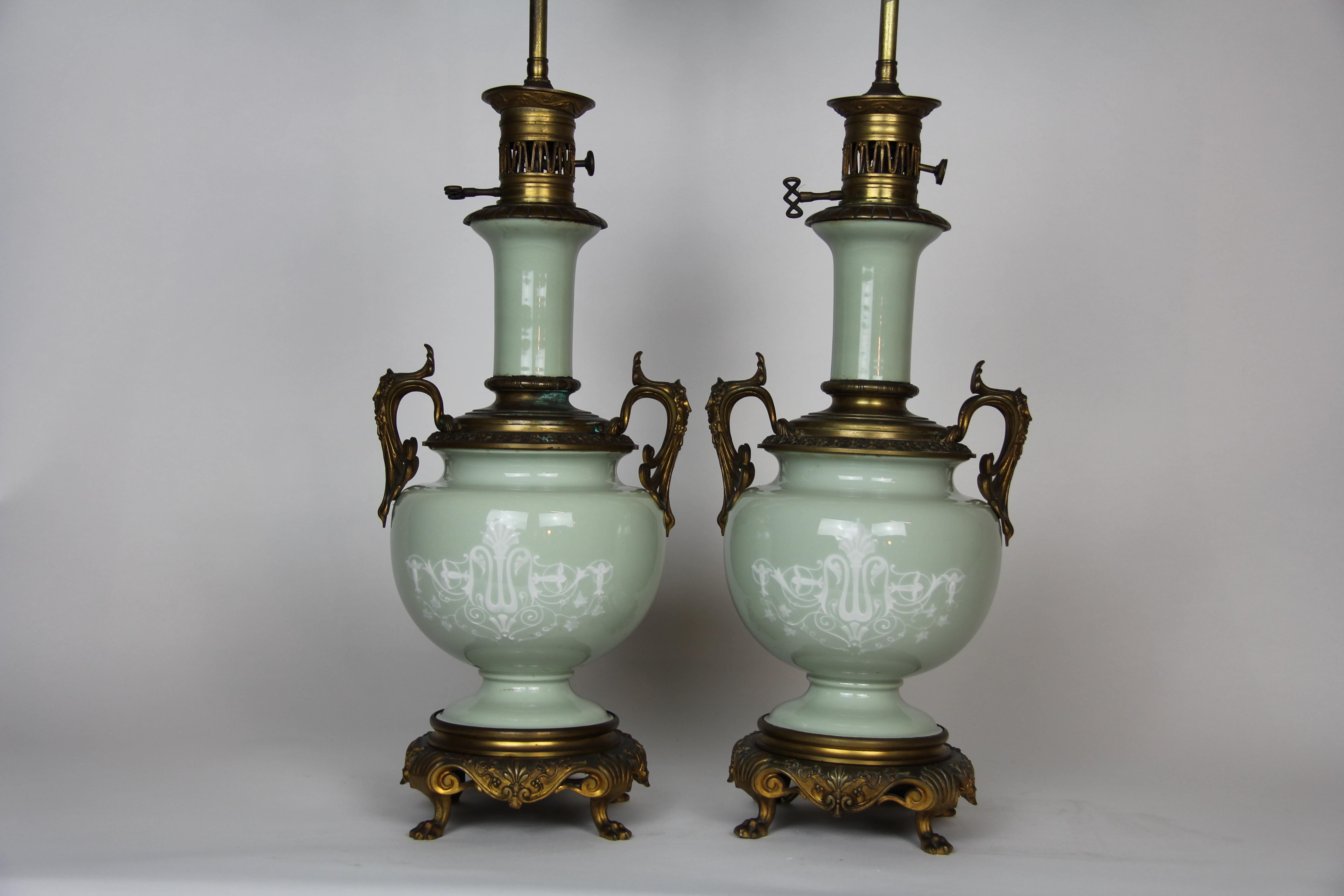 A beautiful pair of French Louis XVI style gilt bronze mounted double sided Pate Sur Pate Celadon ground lamps. Each lamp is beautifully designed with pate sur pate figures of maidens and putti. On the reverse of each lamp are elaborately designed