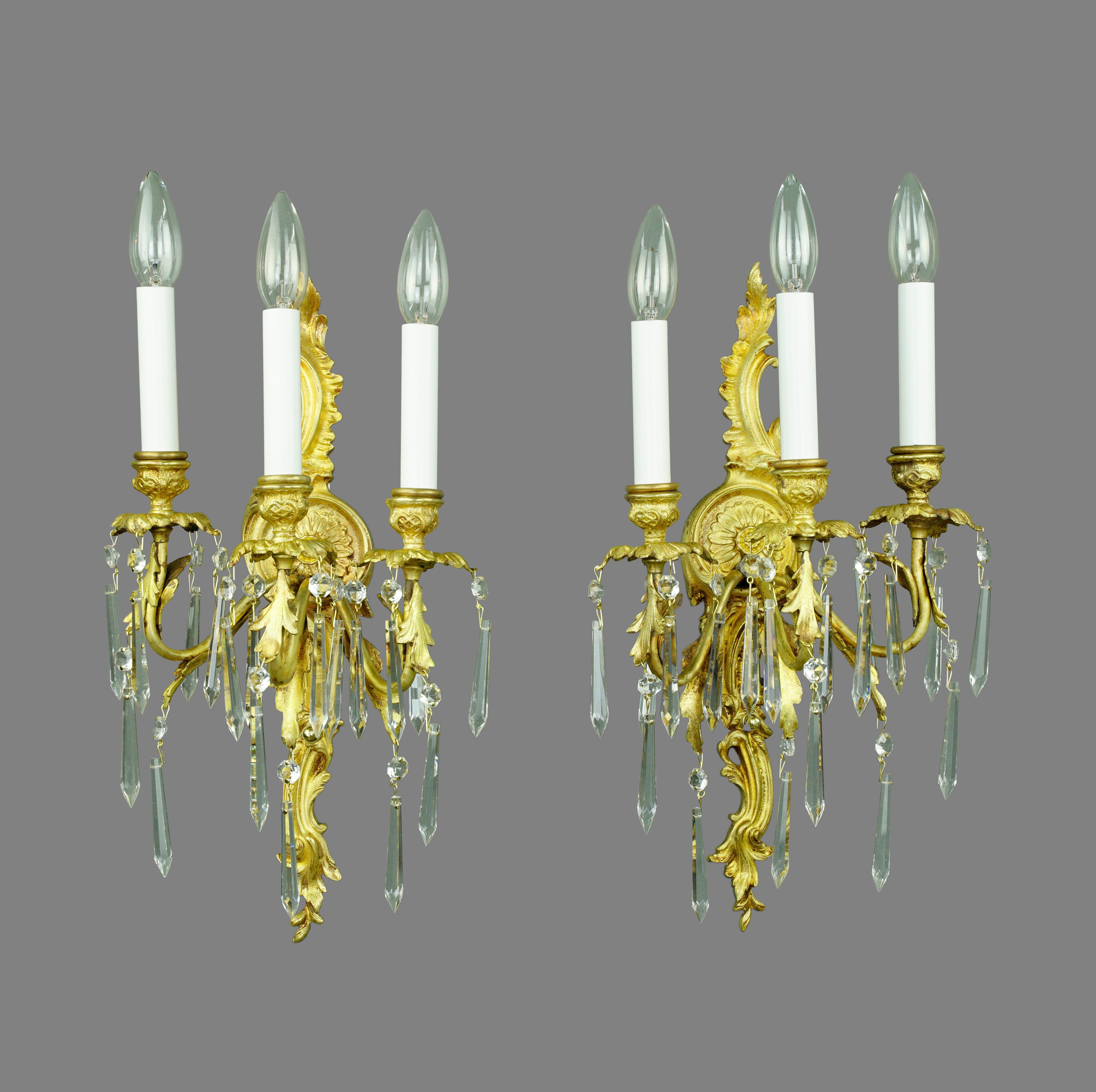 Méticuleusement restaurées, ces appliques murales présentent des détails complexes en bronze doré et des cristaux étincelants. Les trois bras dégagent une élégance intemporelle, alliant l'artisanat français à un design luxueux. Illuminez votre