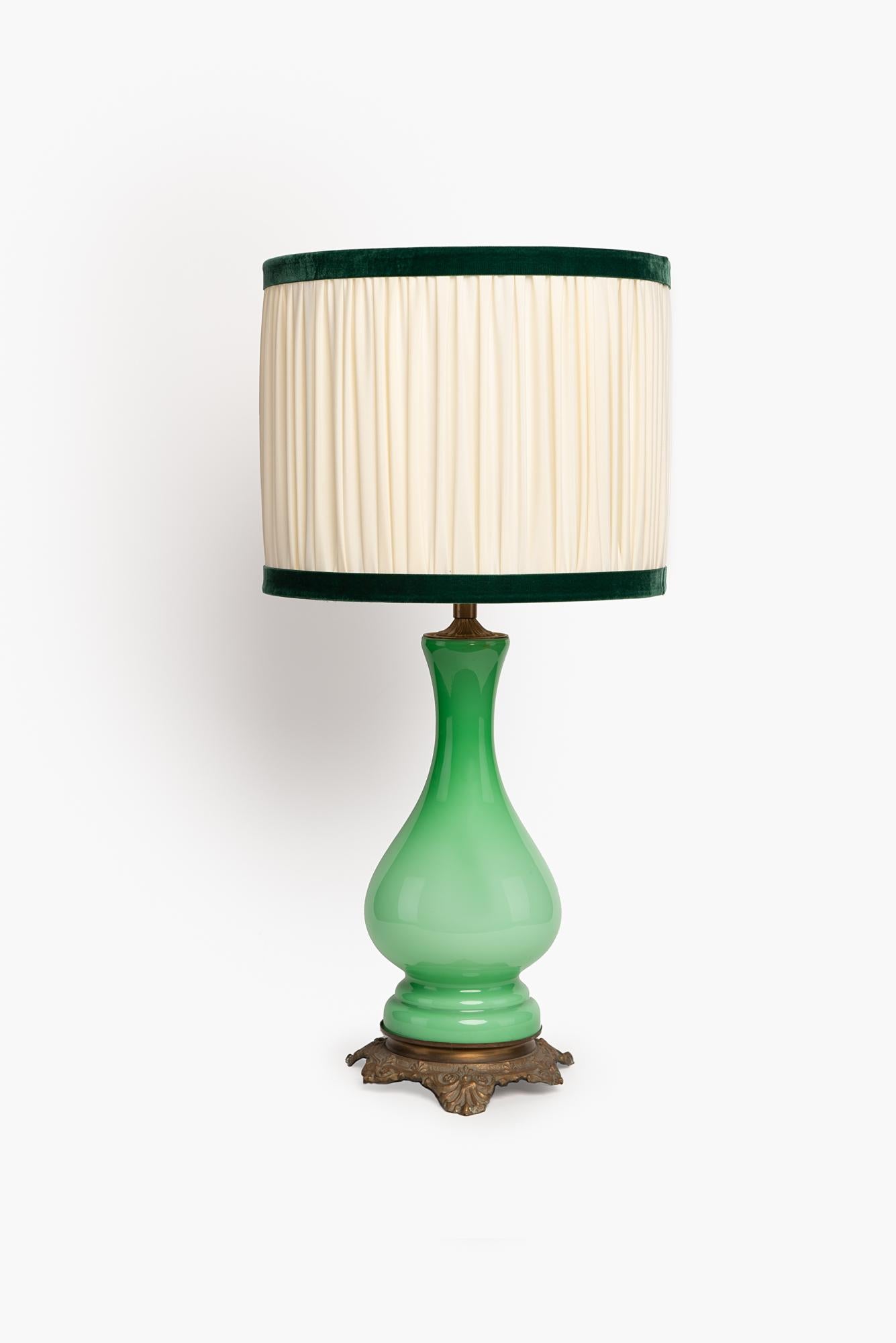 Elegant pair of lamps in green opaline glass; originally these lamps were oil lamps, over time the mechanism with the wick was removed, they were then electrified to make them more comfortable and modern use; the body, completely smooth, is in an