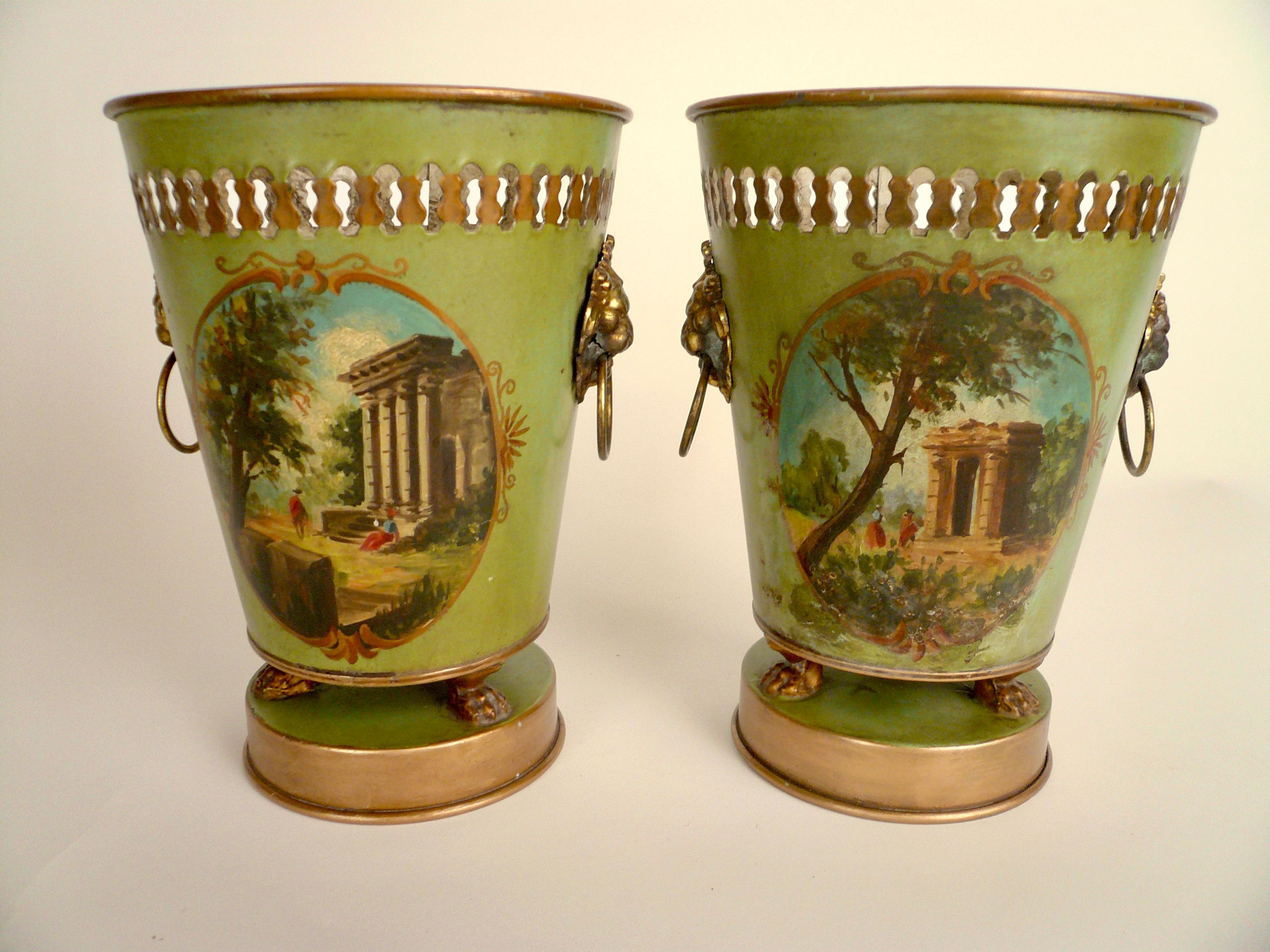 This handsome pair of French tole cachepots feature hand painted Classical landscapes, and gilt brass loin head and ring handles. 