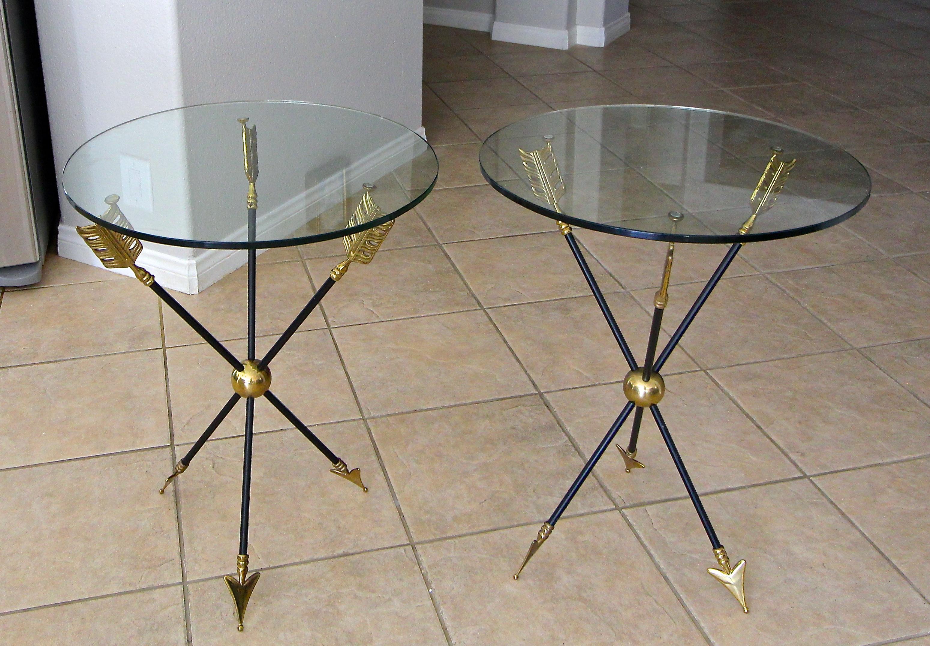 Pair of French Directoire style arrow side or end tables with glass tops, attributed to Maison Jansen. Detailing of the arrow motif includes solid cast brass tip and feathers connected by black iron shaft. Nice original patina to brass.