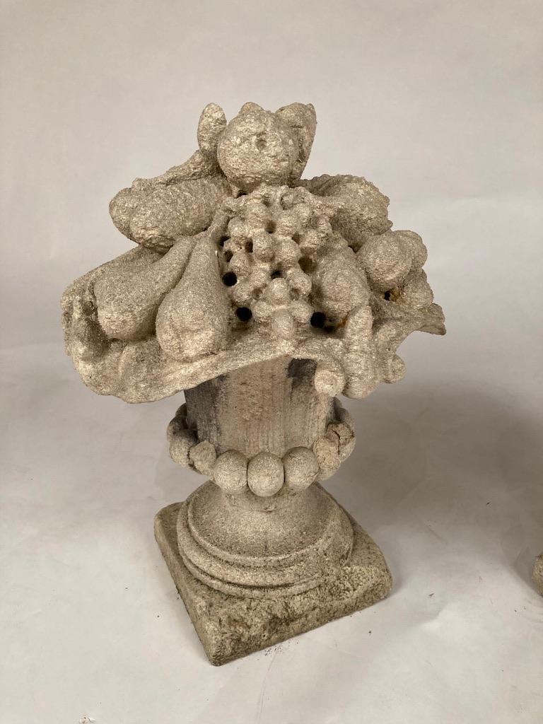 Lovely pair of French Rococo style limestone urns with cornucopia of fruits and vegetables. Weathering from years of outdoor exposure give these urns a genuine time worn appeal. An exuberant addition to any garden or interior. Each urn is two pieces