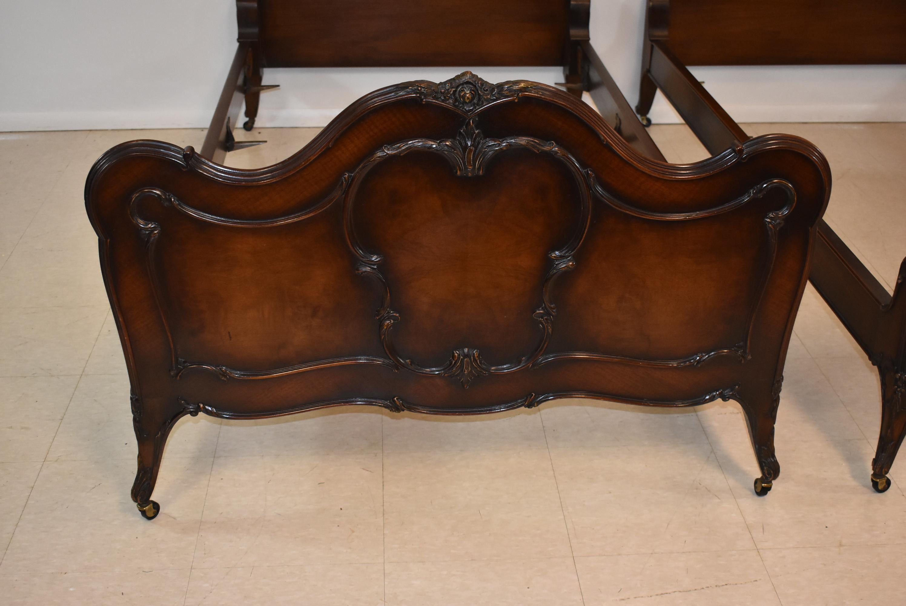 Pair of French Louie XV style walnut twin bed frames by Irwin Furniture. Figured walnut panels with applied carvings.