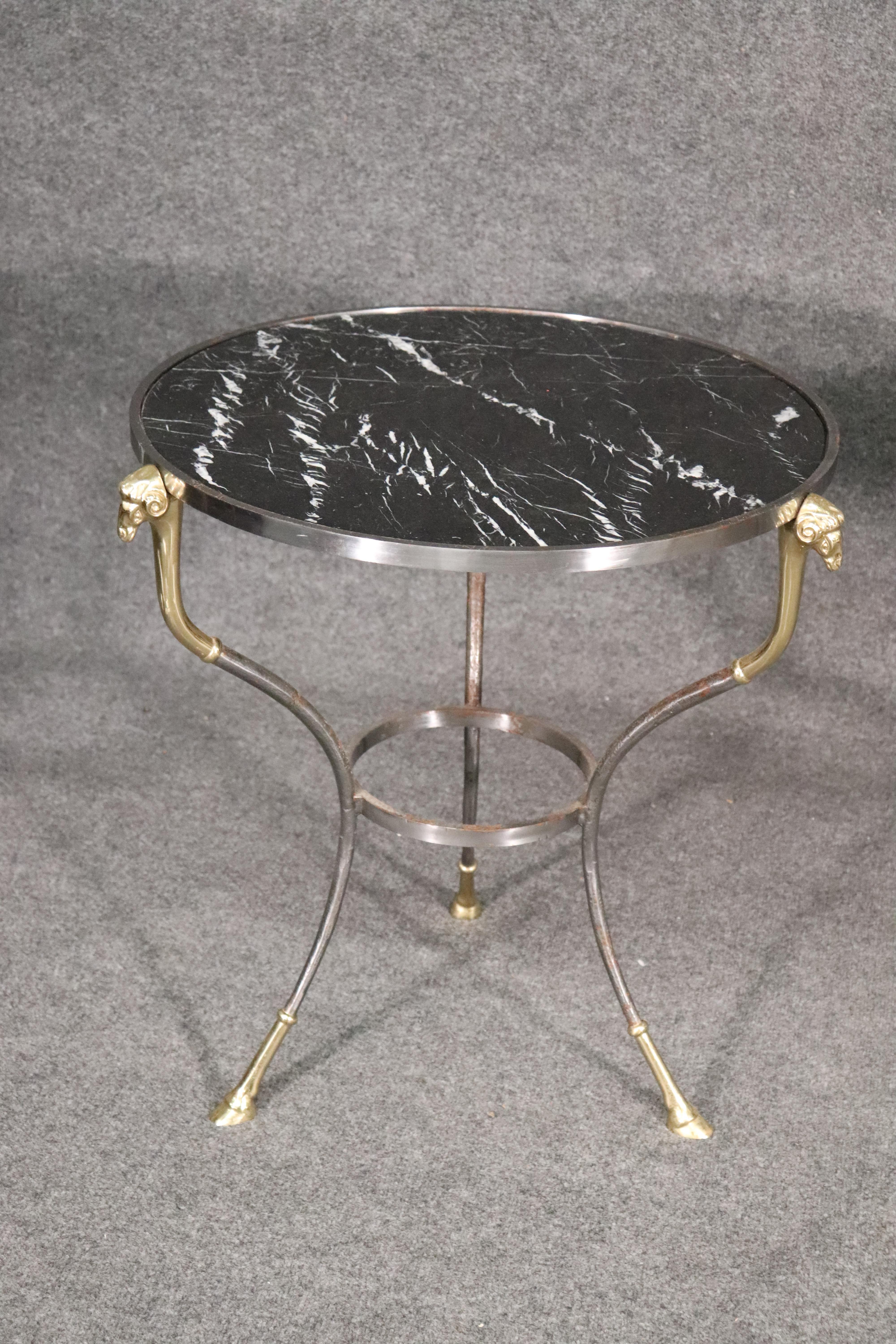 These are beautifully made brass and steel geuridons. The tables feature the classic rams head terminals and cloven hooved feet done in brass. The marble tops are black with white veins. These beautiful tables may be just what you're looking for.