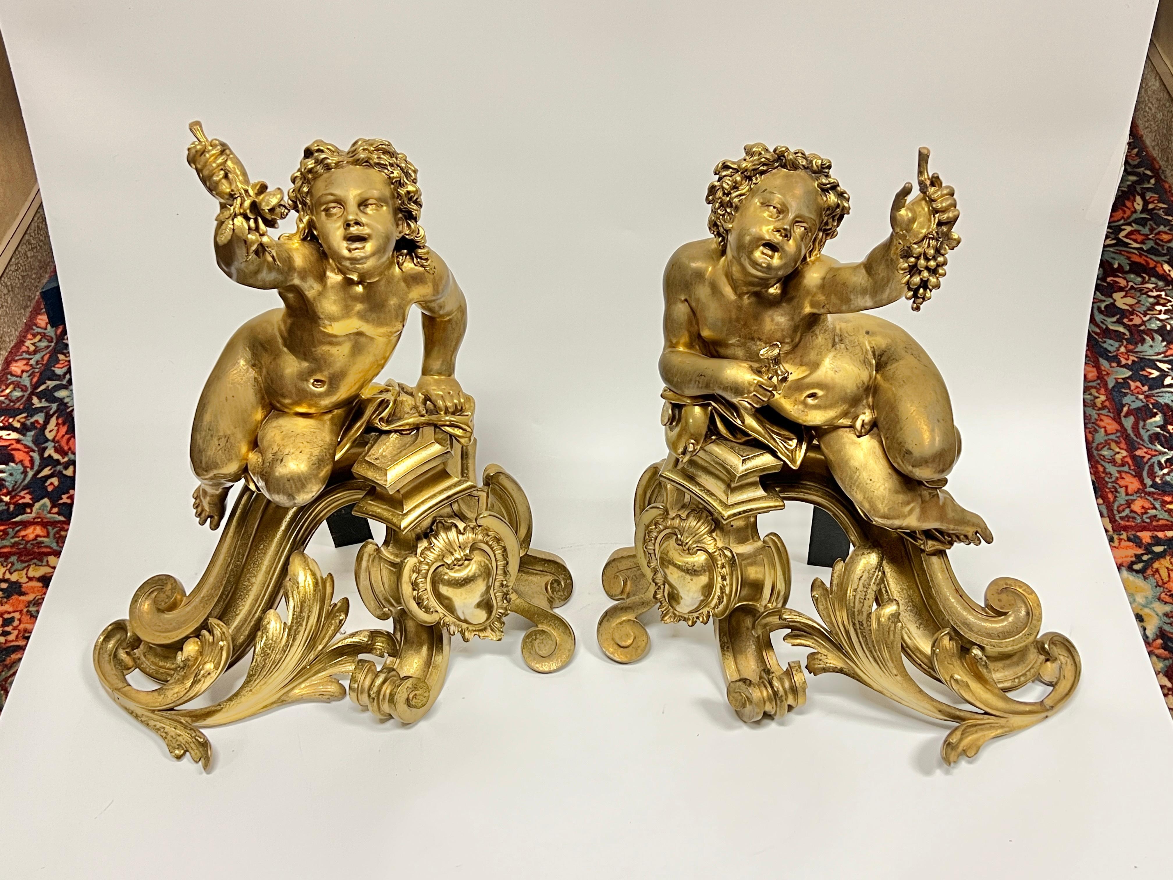 Pareja de morillos (chenets) neoclásicos (s. XIX) de bronce dorado con temática de Baco romano, de estilo francés Luis XVI, que representan querubines sentados sosteniendo racimos de uvas.  Cada una de 24 por 20 por 10 pulgadas.  Aparentemente sin