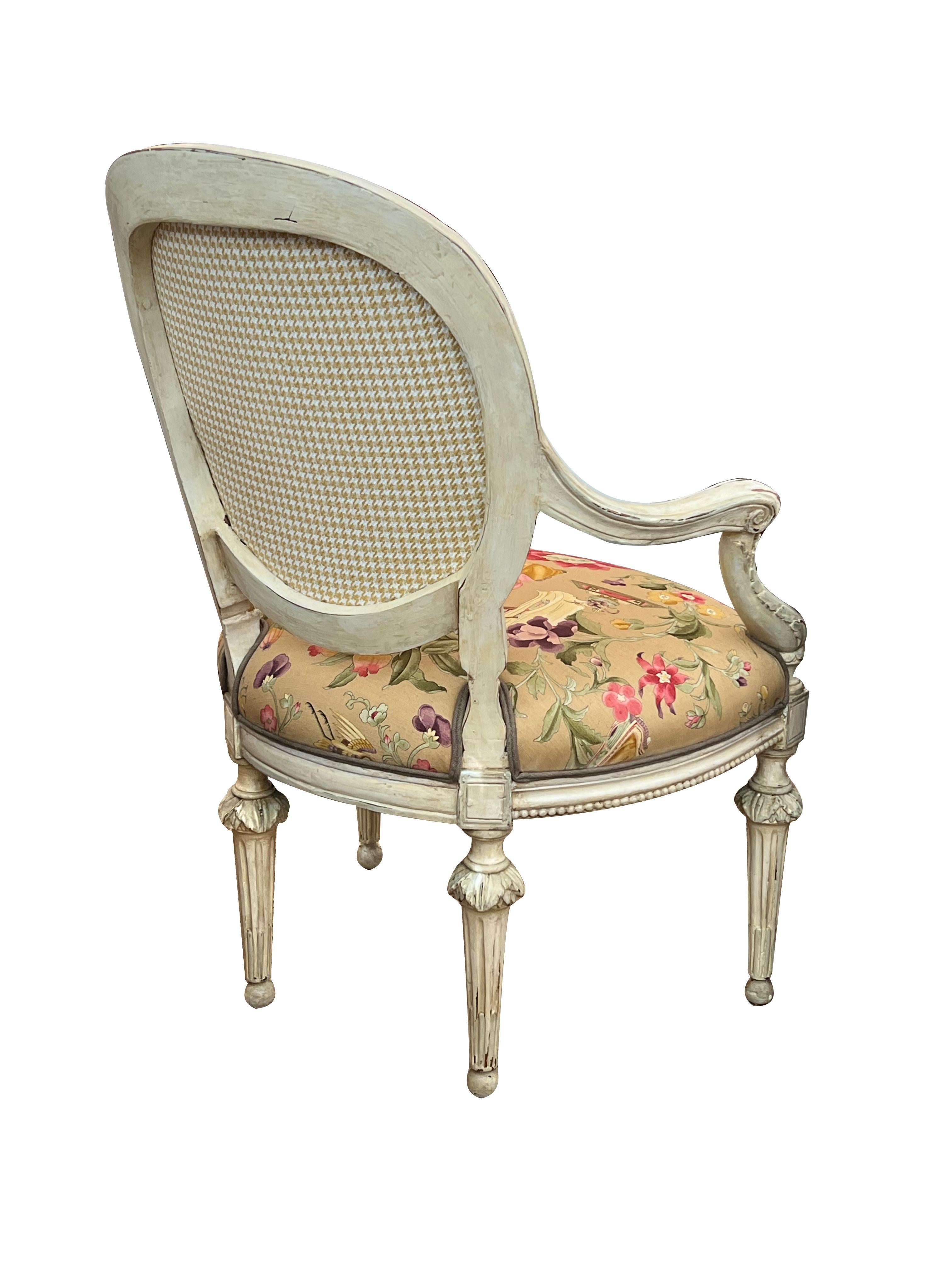 each neoclassical open armchair with beaded framed oval back above a bowed tight seat over a beaded apron flanked by scrolled arms and uprights with acanthus carving; raised on reeded and fluted supports with acanthus collar and ending in a spheroid