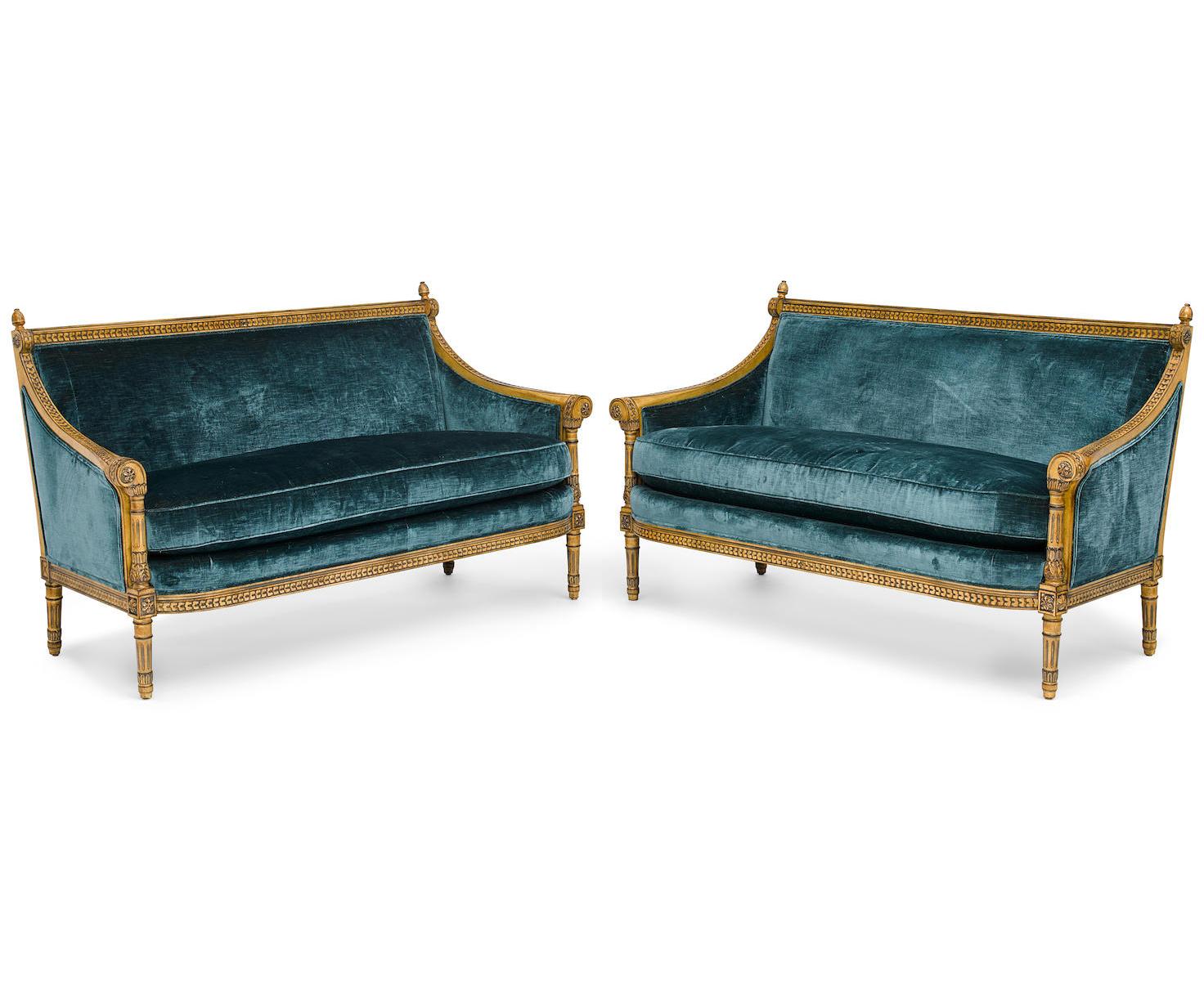 Coppia di divani bergère intagliati e dorati Laqué in stile Luigi XVI. L'elegante coppia di divani intagliati, rivestiti in velluto blu, con schienali e fianchi imbottiti e seduta a cuscino, i braccioli a fasce decorate con rosette floreali e
