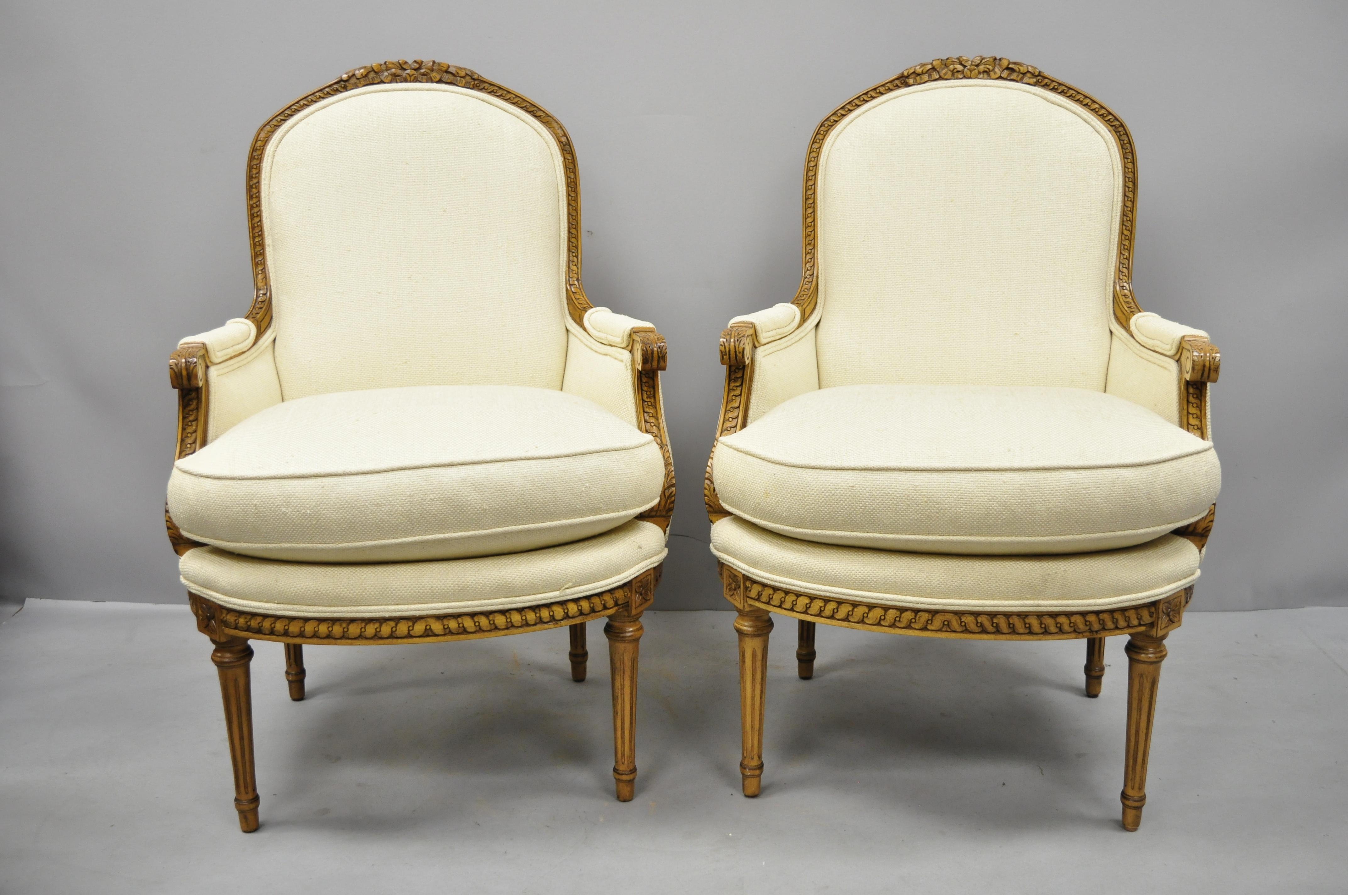 Pair of French Louis XVI style upholstered bergere armchairs by Greenbaum Interiors. Items feature tan burlap upholstery, solid wood construction, upholstered armrests, distressed finish, Serial number (H-309 chair), tapered legs, quality