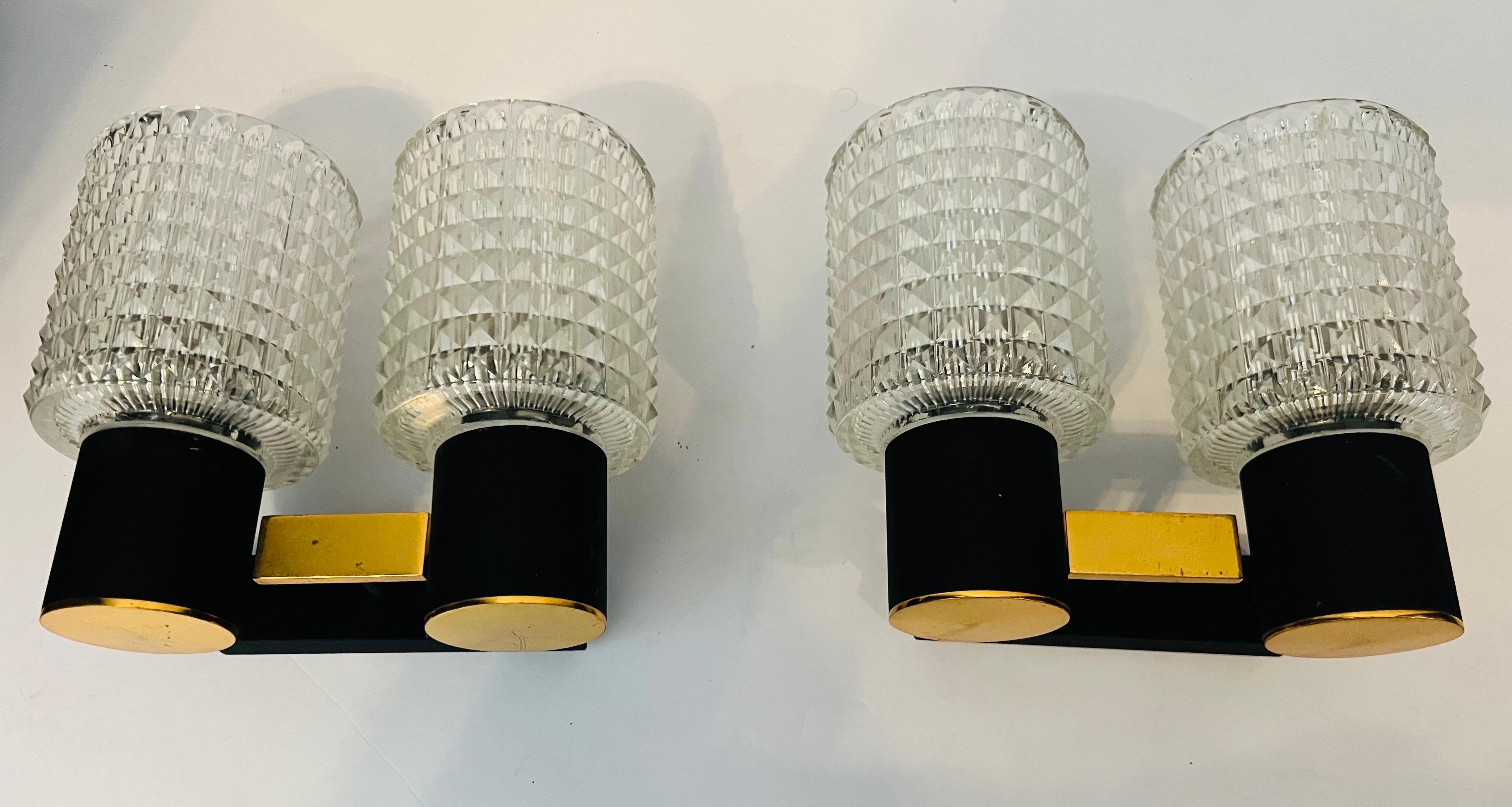 An original pair of French 1960s sconces composed of golden polished brass and black enamel fixtures with cut crystal glass shades. Made by the lighting company Lunel. Rewired with two candelabra sockets each.