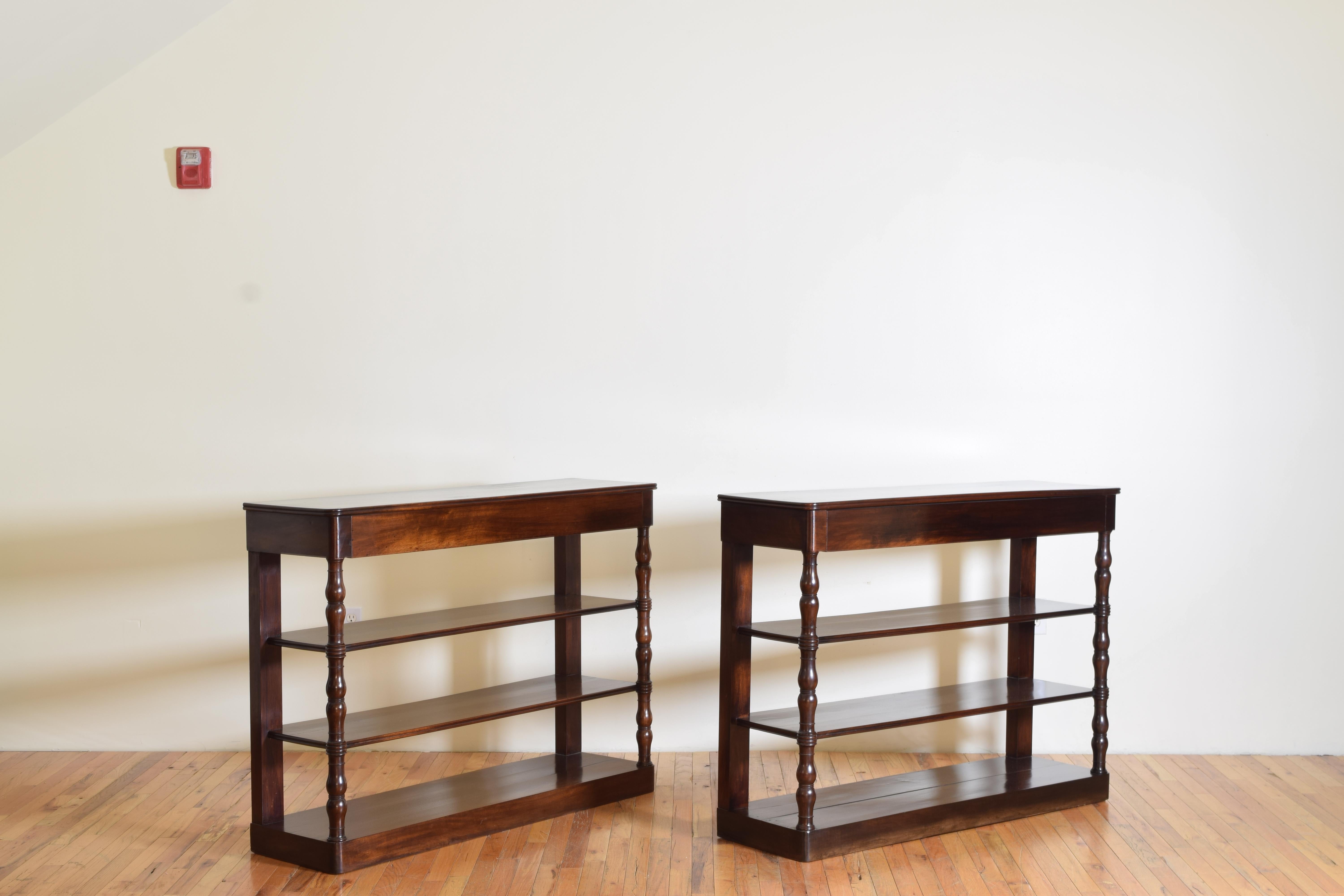 Each having a rectangular top with rounded front corners and molded edges above larger drawers with hidden hand pulls, raised on turned front supports and rear flat supports, connected by two tiers of shelves, the bottom shelves also the bases with