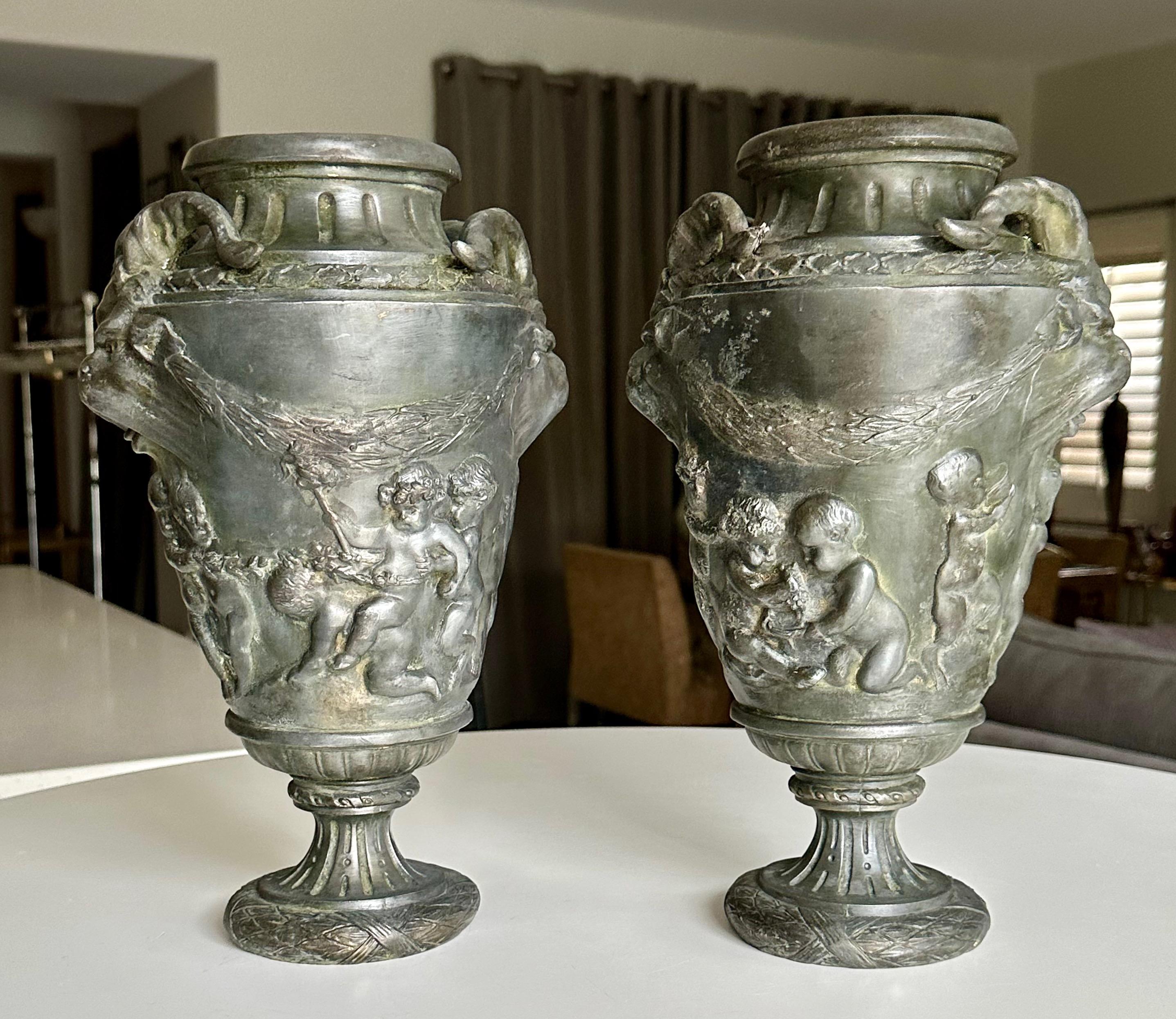 Coppia di antiche urne a forma di vaso greco con manici a maschera di satiro, corpo con putti o cherubini in alto rilievo. Firmato 