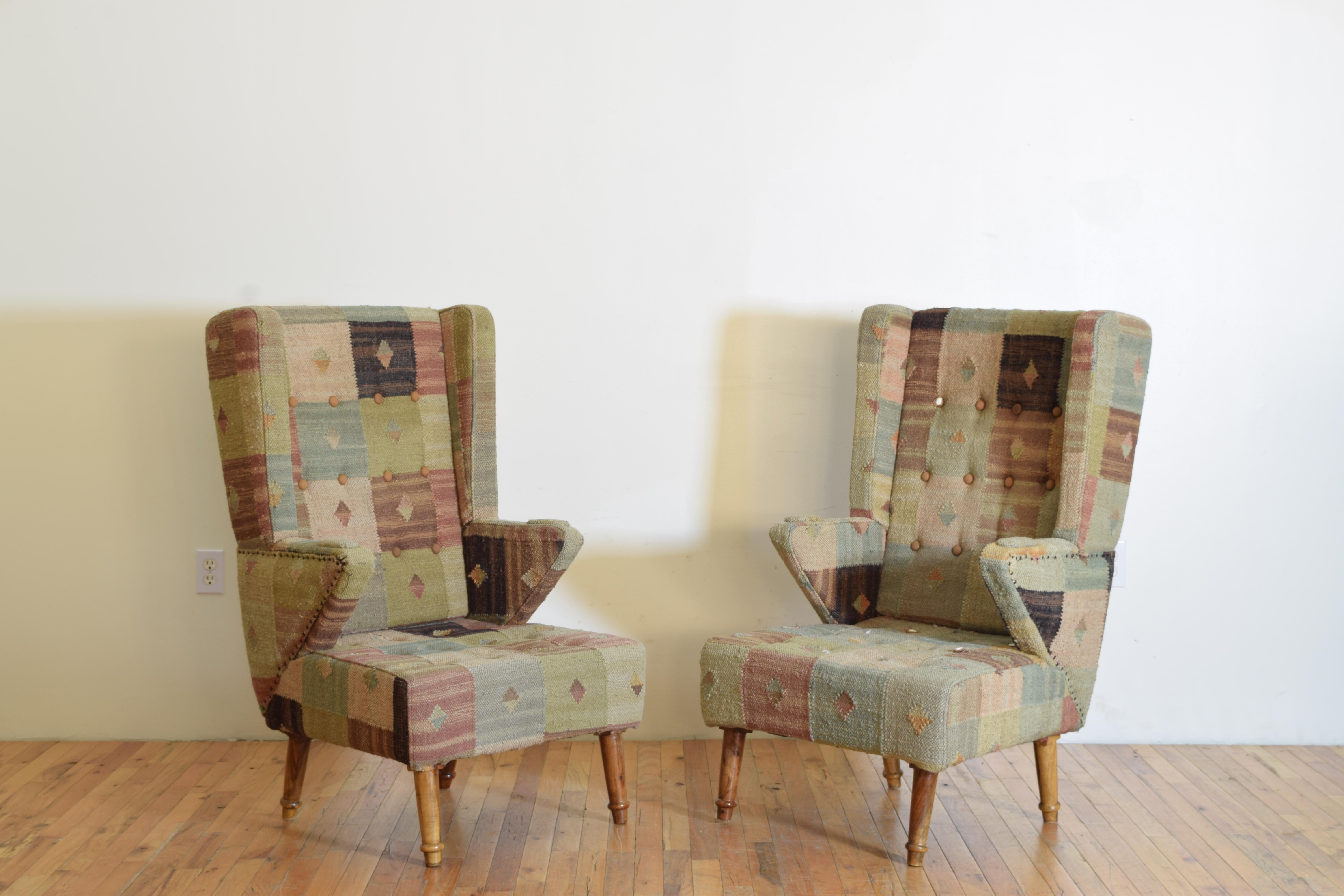 Paire de grandes et confortables bergères très stylisées recouvertes de tissu kilim tissé, les chaises reposant sur des pieds ronds évasés et effilés.