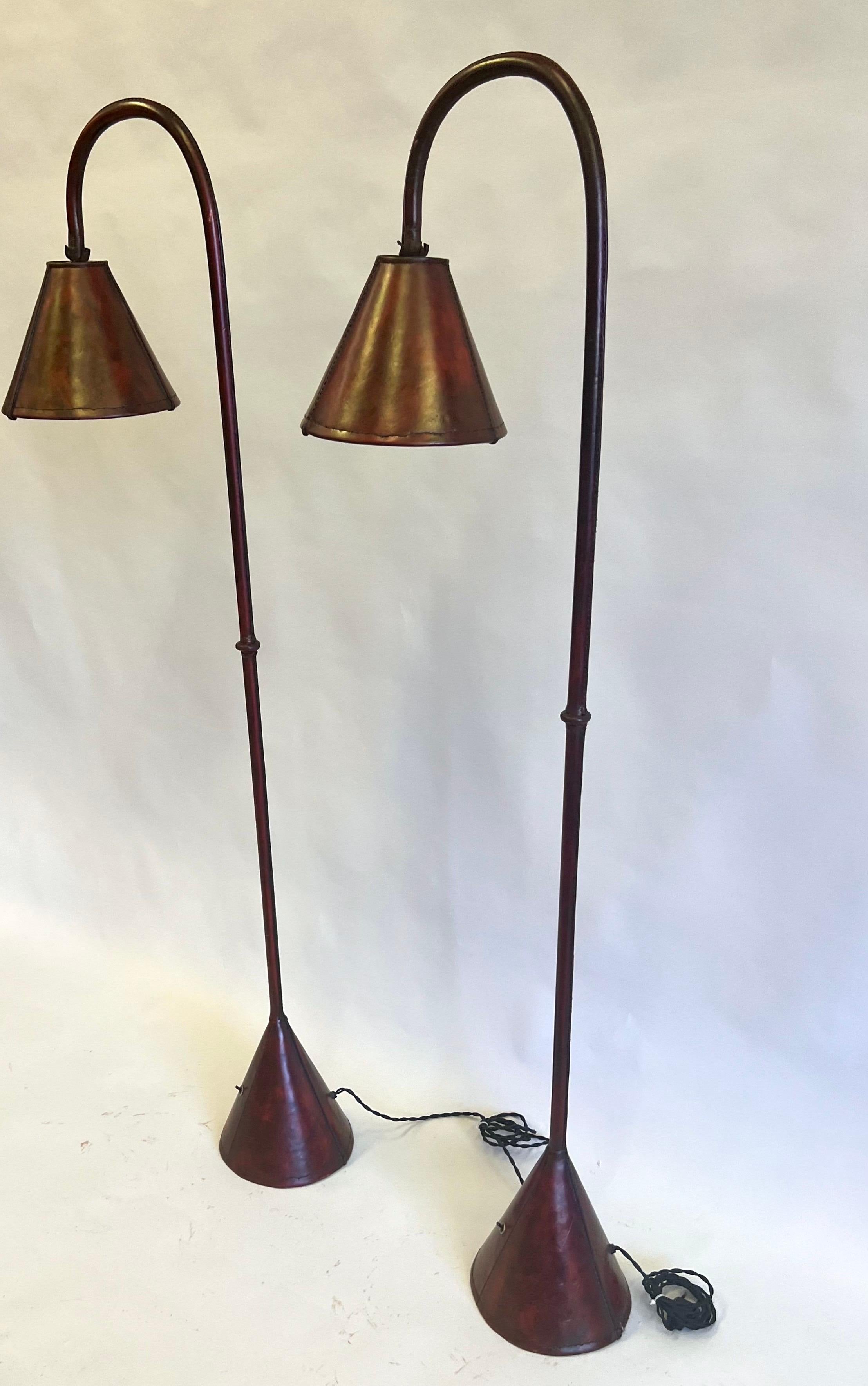 Ein elegantes Paar französischer Stehlampen aus der Mitte des Jahrhunderts in handgenähtem dunkelrotem/burgundfarbenem Leder des französischen Meisters des 20. Jahrhunderts, Jacques Adnet, um 1955. Dieses klassische, handgefertigte Modell des