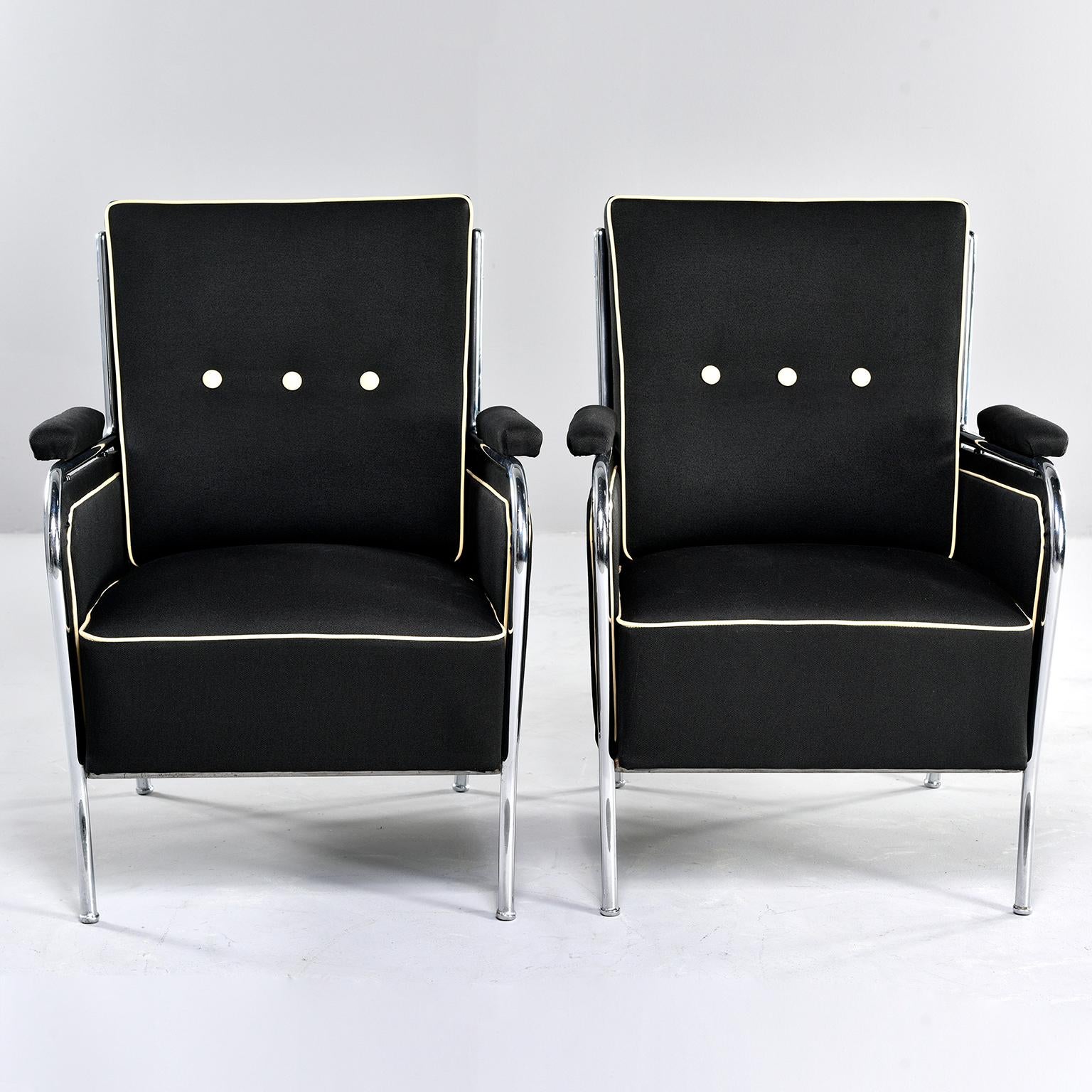 Pair of French chrome-framed club chairs have been newly upholstered, circa 1940s. Black cotton blend fabric has a slubby texture and chairs are trimmed with contrasting ivory colored leather welting and buttons. Measures: Padded arms are 24.75”