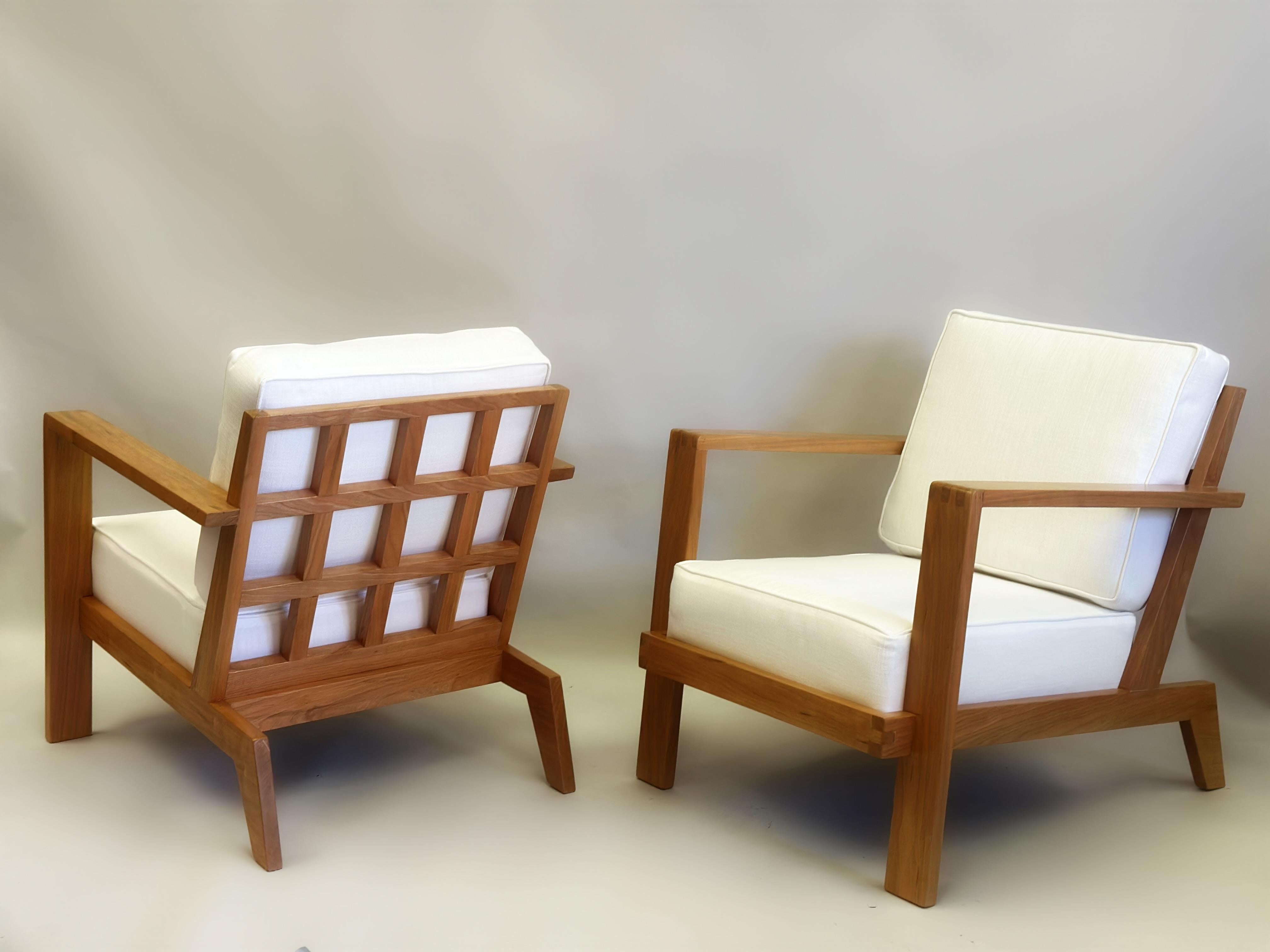 Paire de fauteuils, clubs ou chaises longues de style français moderne du milieu du siècle dernier en cerisier massif par René Gabriel, vers 1948. Les chaises sont dotées d'accoudoirs et de pieds sabres inclinés, ainsi que de dossiers en forme de