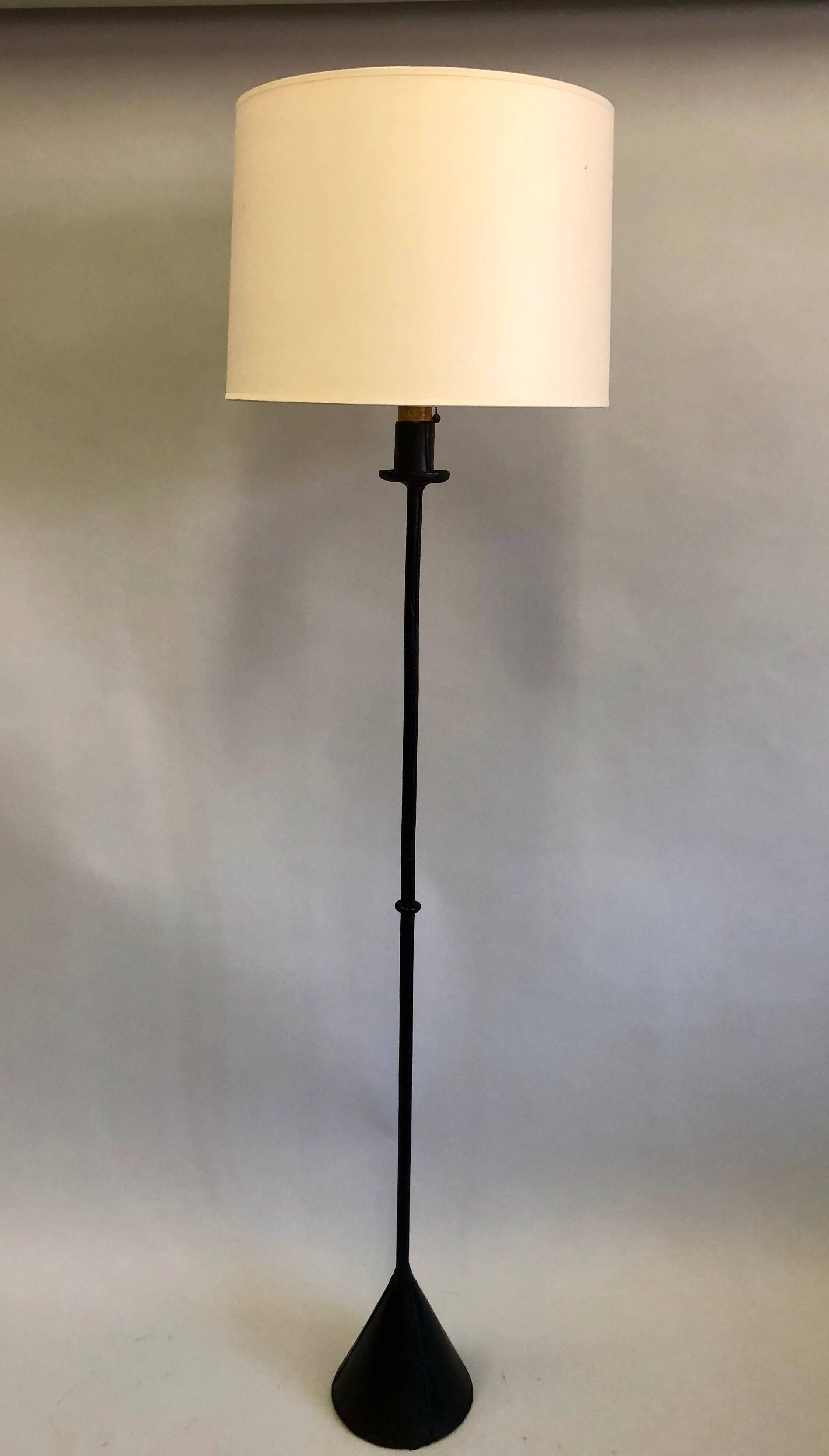 Elegant pair of French Mid-Century Modern handstitched black leather floor lamps by Jacques Adnet, 1940-1950.

The standing lamps have a dramatic cone base. Black leather is wrapped around base and stem and is handstitched. 

Base diameter is 8