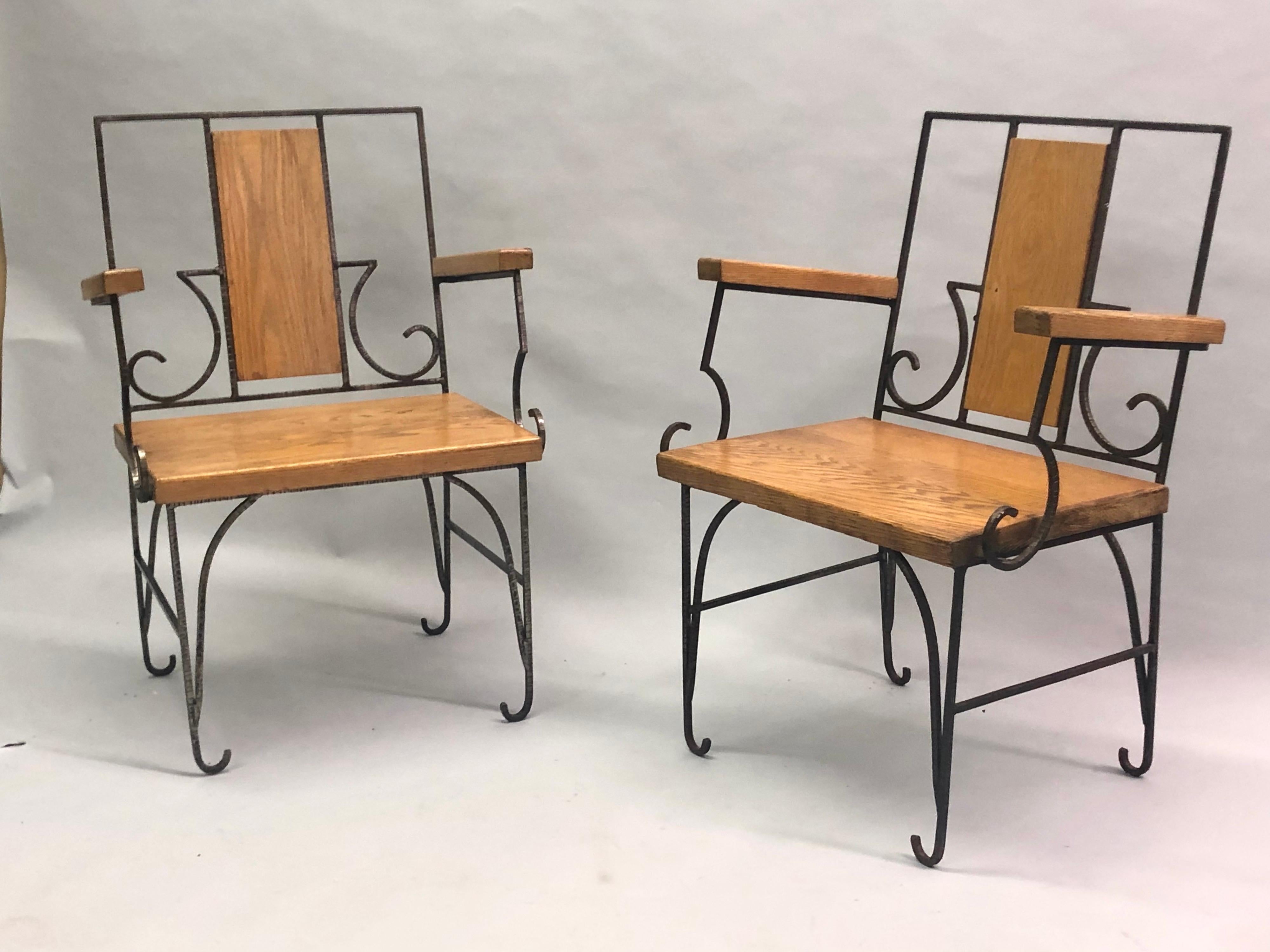 Elegant Pair of French Mid-Century Modern Neoclassical armchairs in hand hammered and chiseled wrought iron with thick, oak seats and backrests in the style of Marc Duplantier. The lounge or club chairs present a refreshing, open, transparent form