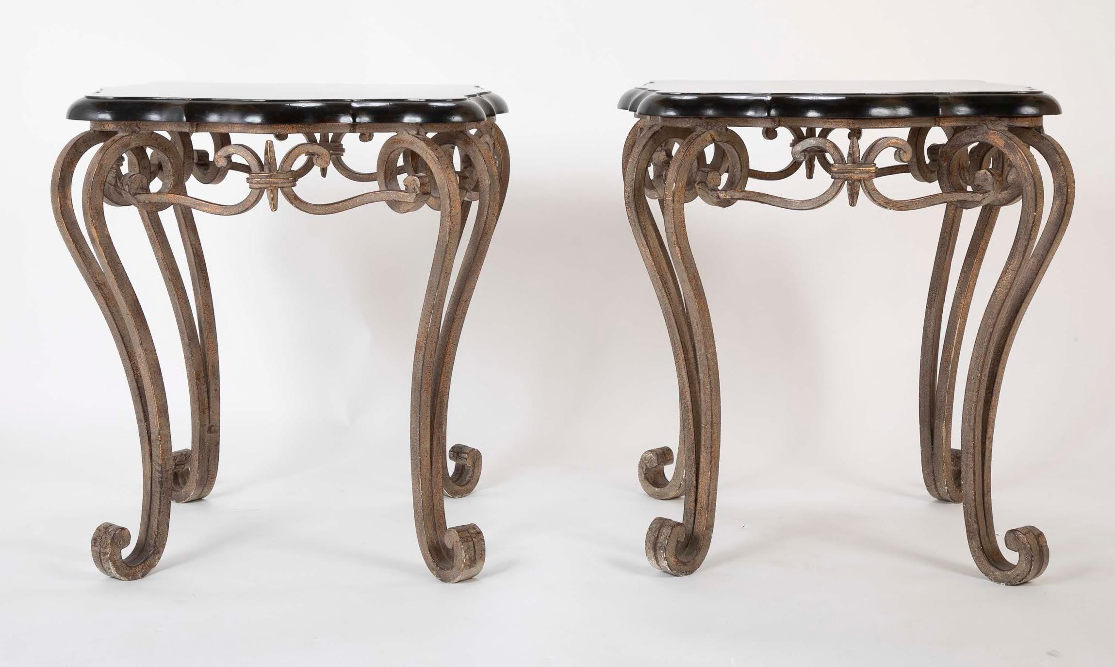 Pair of wrought iron side tables with shaped black lacquered tops over scrolling cabriole legs with a silvery gray finish. These impressive tables have real presence. 
26 inches high by 24 by 24.