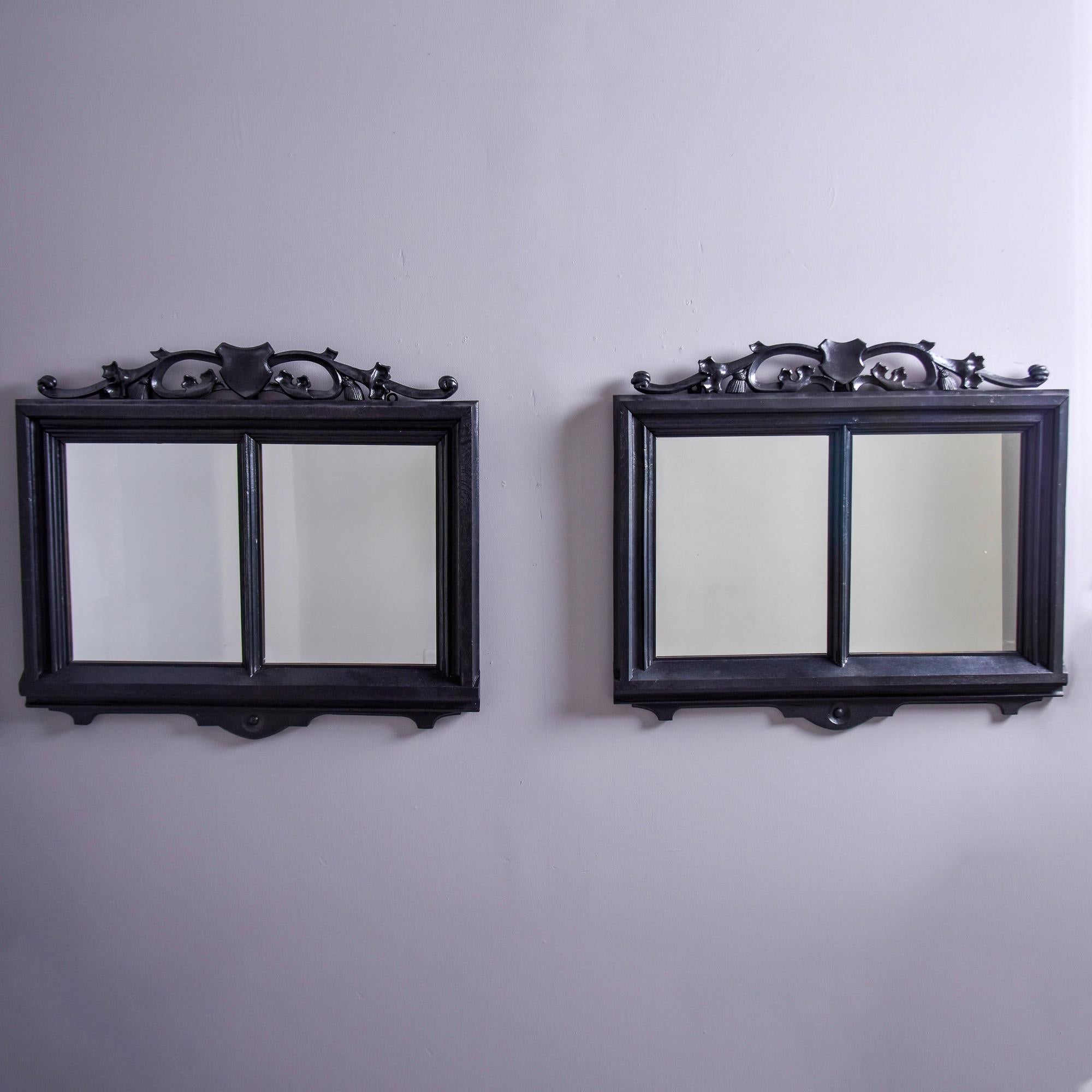 Found in France, this pair of circa 1900 French mirrors have a double pane frame with a black painted finish and carved, open work detailing with a shield at the crest. Sold and priced as a pair. 
