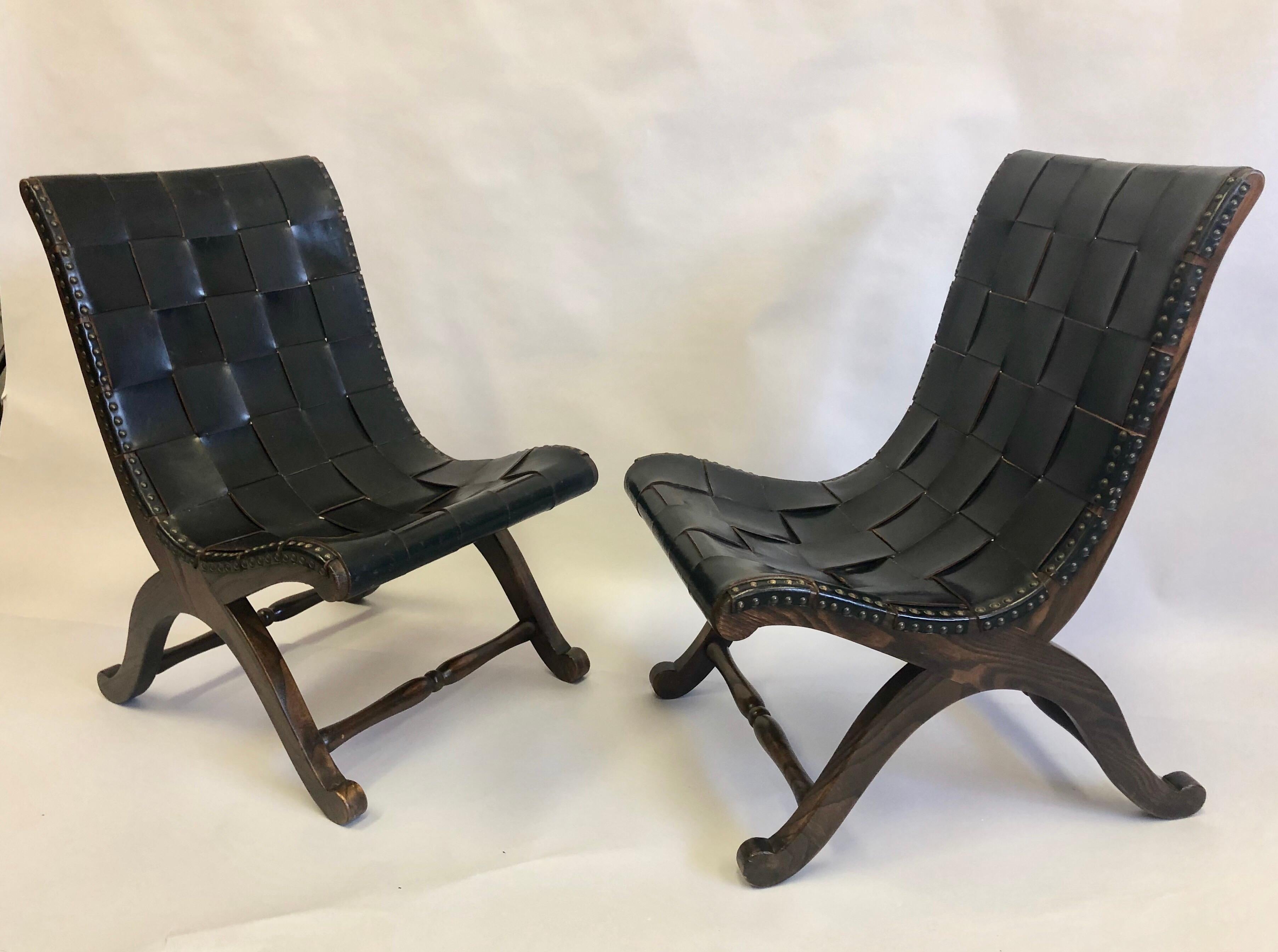 Elegant and timeless pair of French Mid-Century Modern neoclassical black leather strap lounge or slipper chairs attributed to Pierre Lottier. The walnut wood frames are arranged in a classical curile X-form and the black leather straps are