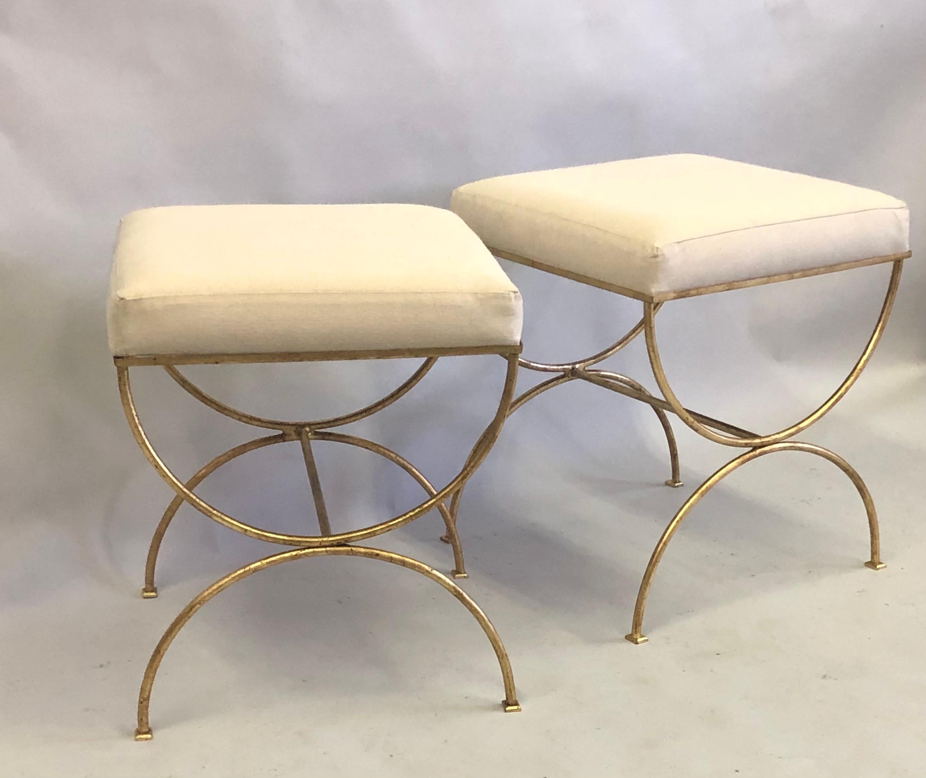 Elegant Pair of French Mid-Century Modern neoclassical benches / stools in the style of Jean Michel Frank. The pieces are in a classic curile form in gilt wrought iron with the seats covered in a heavy cotton.
Measures: H 21 x 18 x 18.