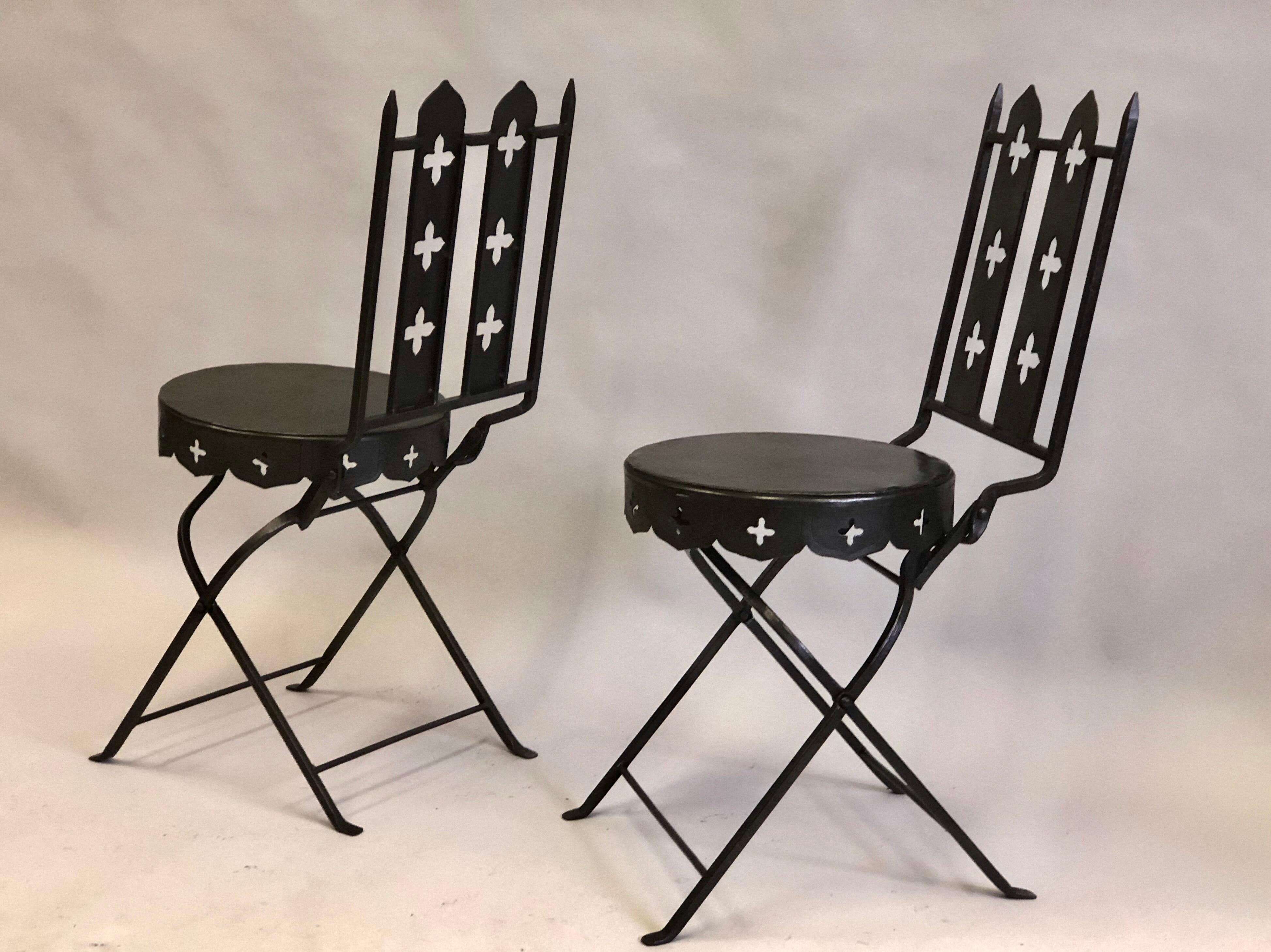 Pair of French Mid-Century Modern neoclassical hand forged iron folding chairs attributed to Gilbert Poillerat. 

Gilbert Poillerat embraced Neo-Medieval traditions utilizing and welded them to either sober, modern or dramatic, Baroque designs.