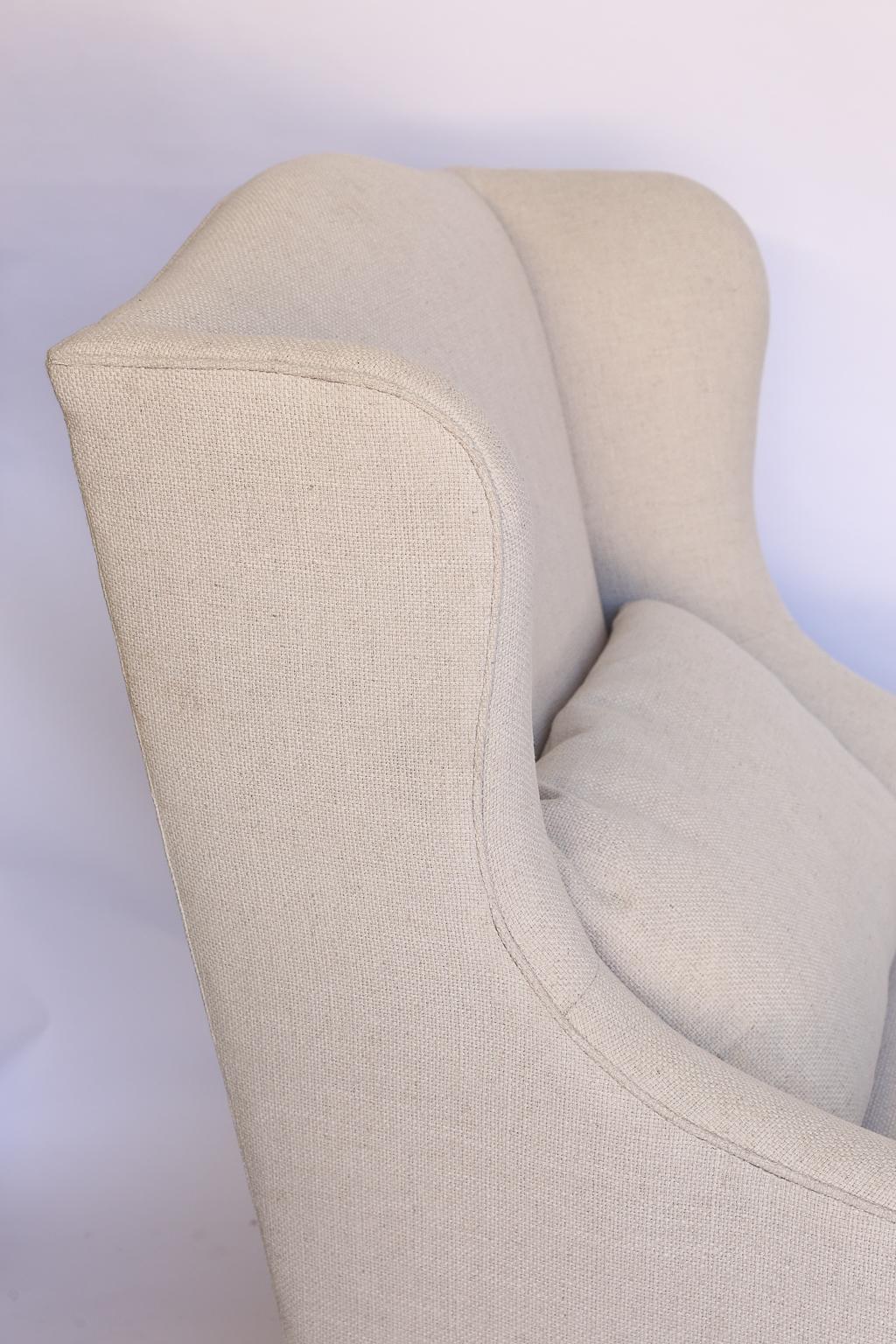 Found in France, this is a pair of French mutton leg, Os de Mouton, wingback armchairs. The chairs have been newly upholstered, with new padding and fill, in an off-white linen blend fabric. The chairs feature a wide seat and have curved side wings