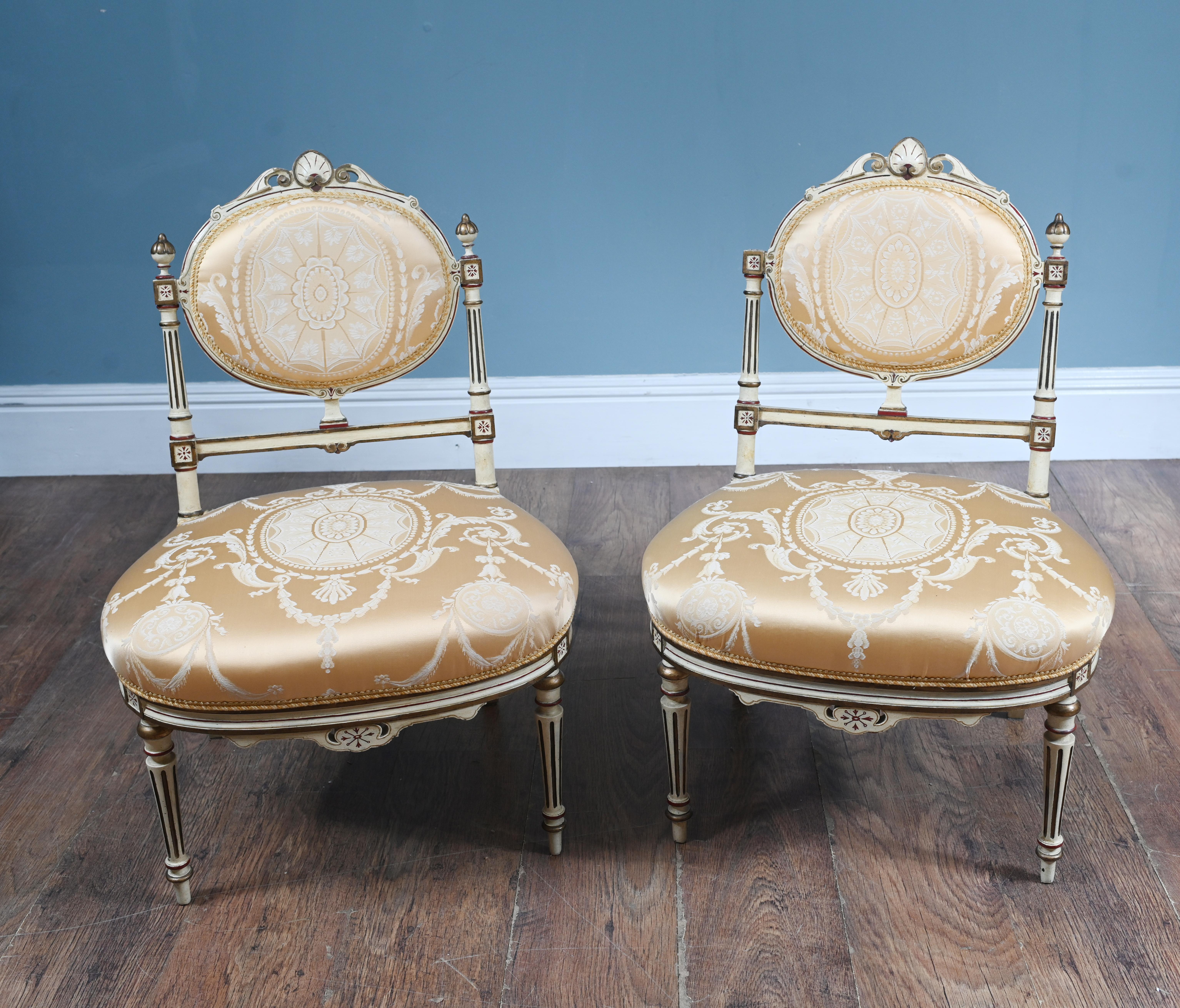 Paire de chaises néoclassiques peintes Circa 1910
Les chaises sont revêtues d'un luxueux tissu de satin doré orné d'un motif damassé ivoire complexe.
Les cadres en bois sont peints dans un ton ivoire pâle avec des accents dorés peints à la main et