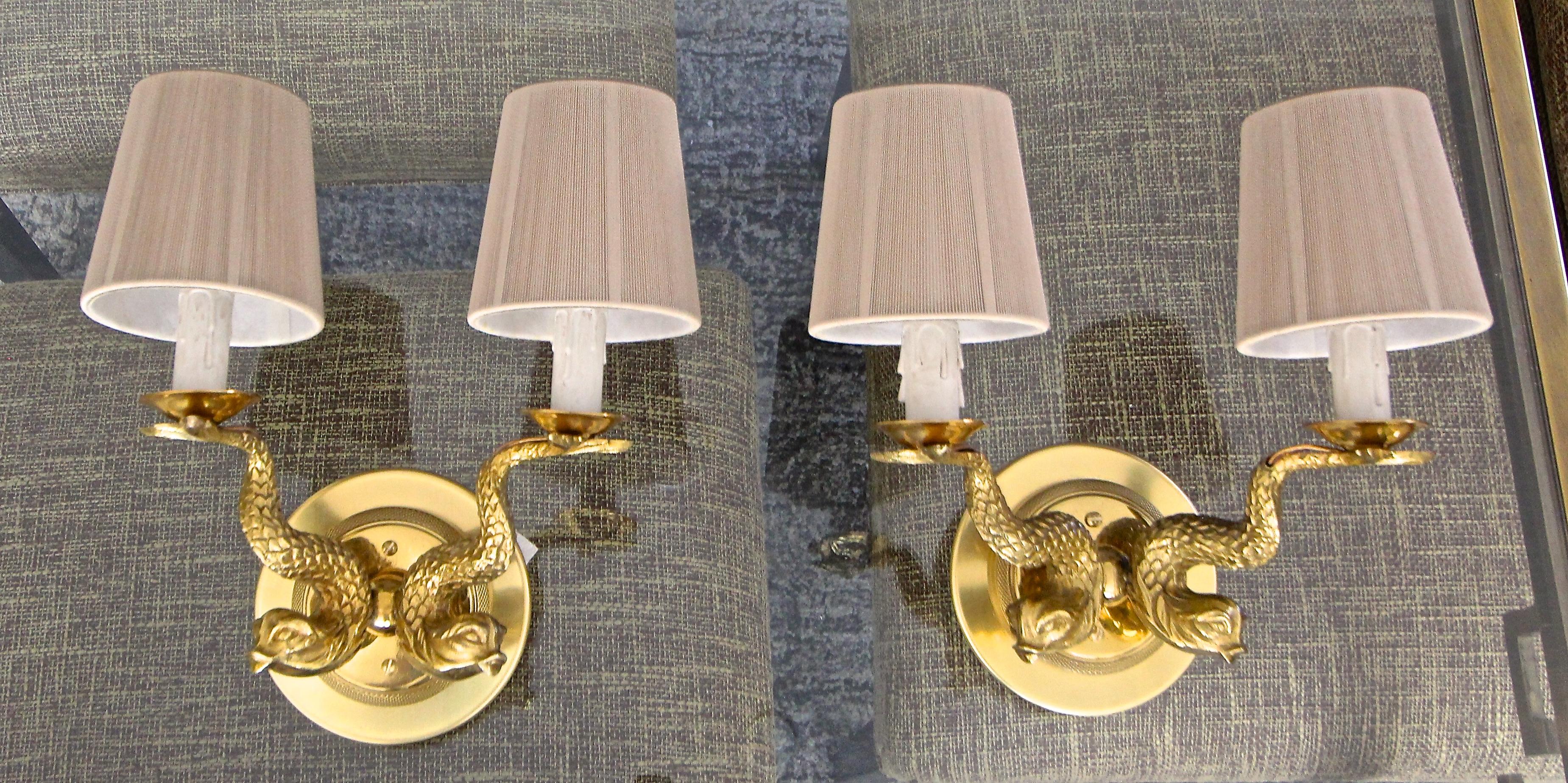 Pair of French two-light French neoclassic style brass wall sconces with dolphin motif. Expertly crafted with high quality detailing throughout. Newly wired with new candelabra sockets. Dimensions: 8.5