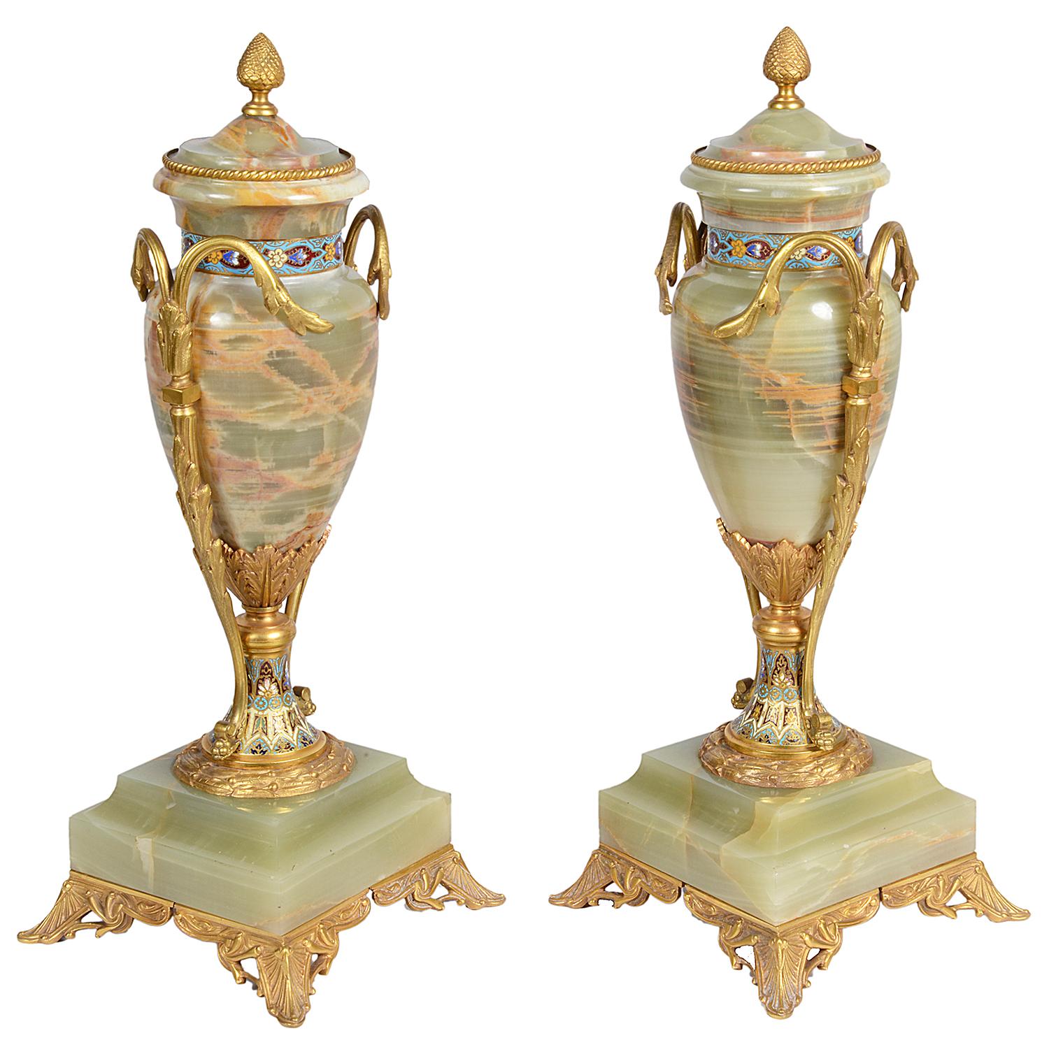 A good quality pair of French onyx, gilded ormolu and champlevé enamel lidded, two handled urns, circa 1890.