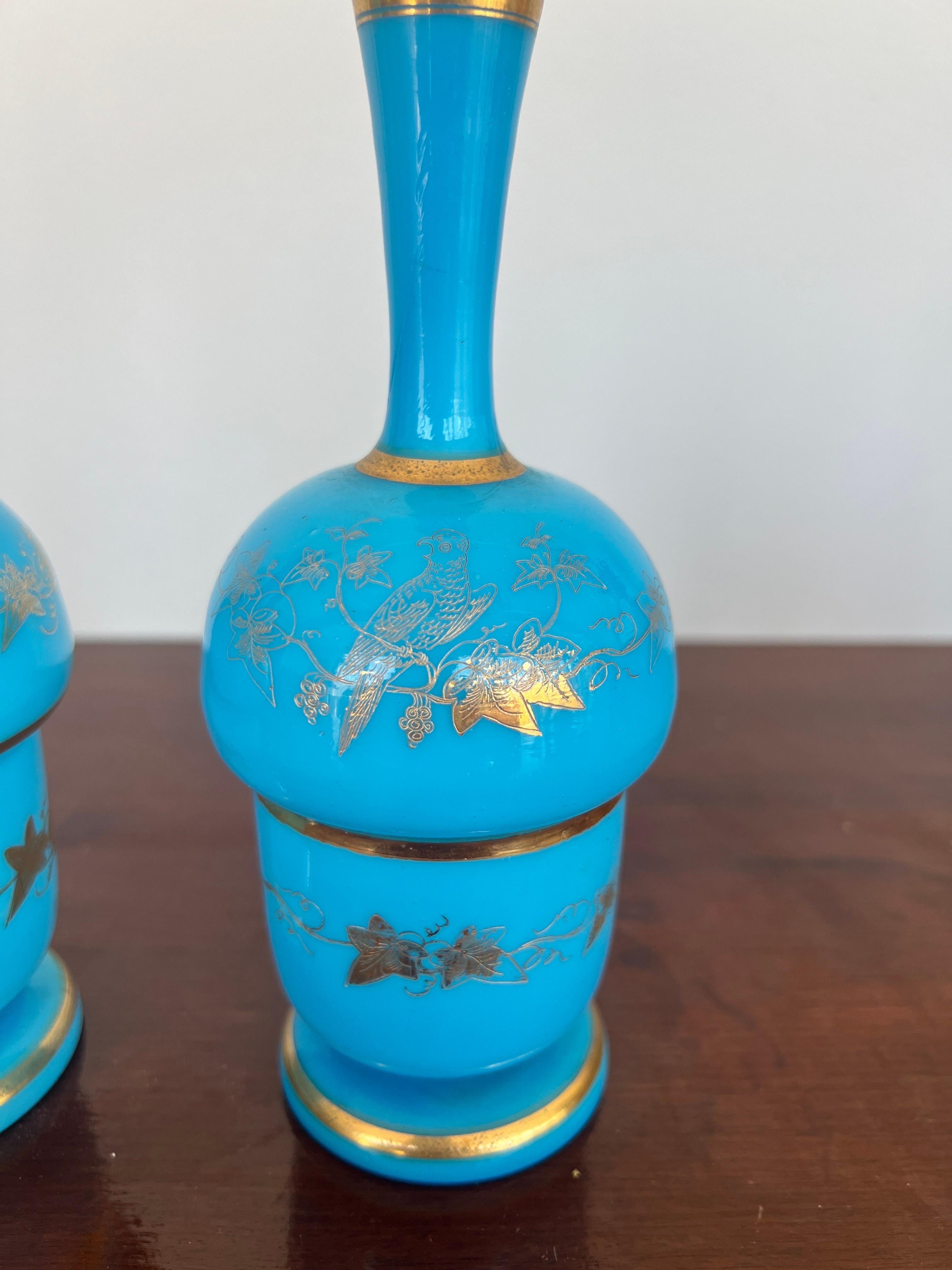 French, 20th century. 
A pair of blue opaline bud vases with gold foliate and vine decoration.