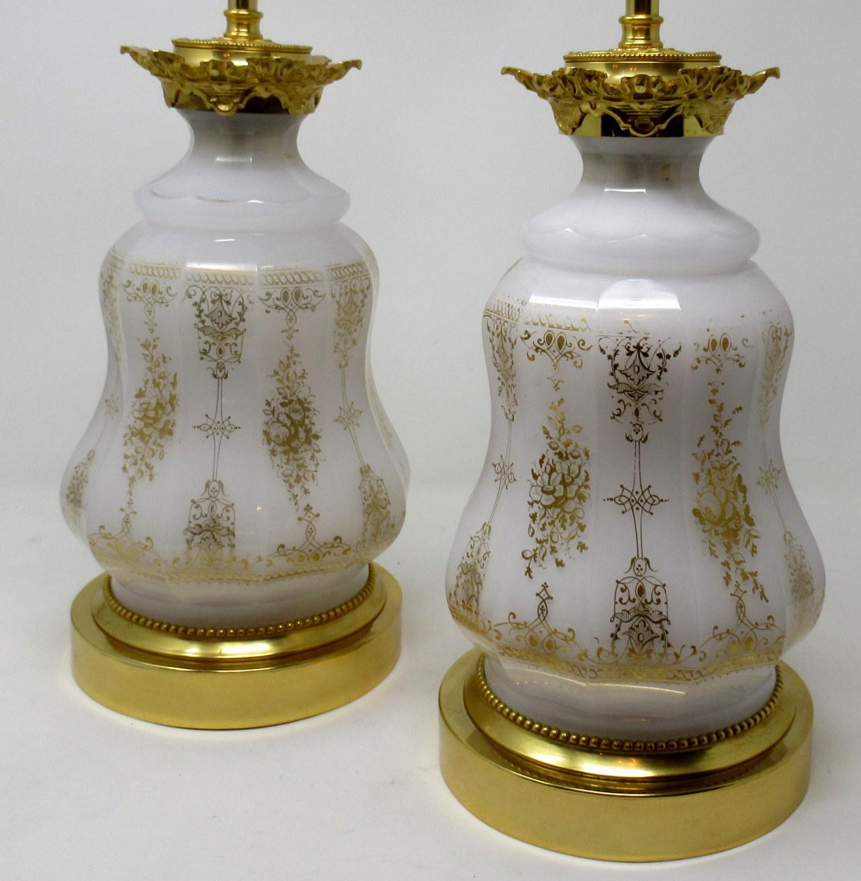 Stunning pair of French Sèvres style opaque glass oil lamps of bulbous outline, now converted to electric table lamps. Last half of the 19th century, of French origin.

The main outer bodies with lavish gilt overlaid scrolling decoration ending on