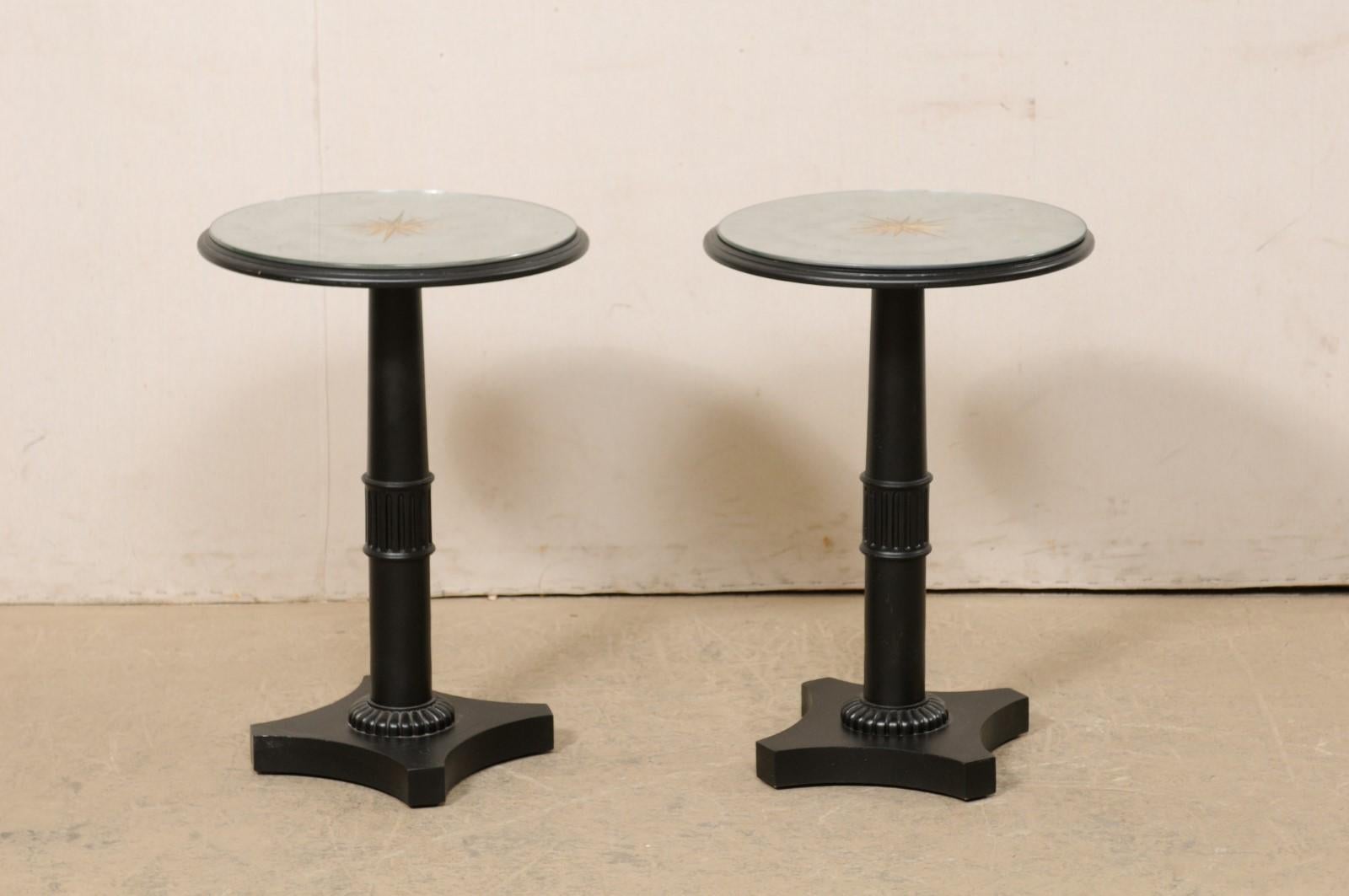 A French pair of wooden pedestal table bases which have been topped with new, artisan crafted, round mirror tops. This vintage pair of side tables from France each feature a rounded pedestal, with a fluted banding accent mid-way up the pedestal,