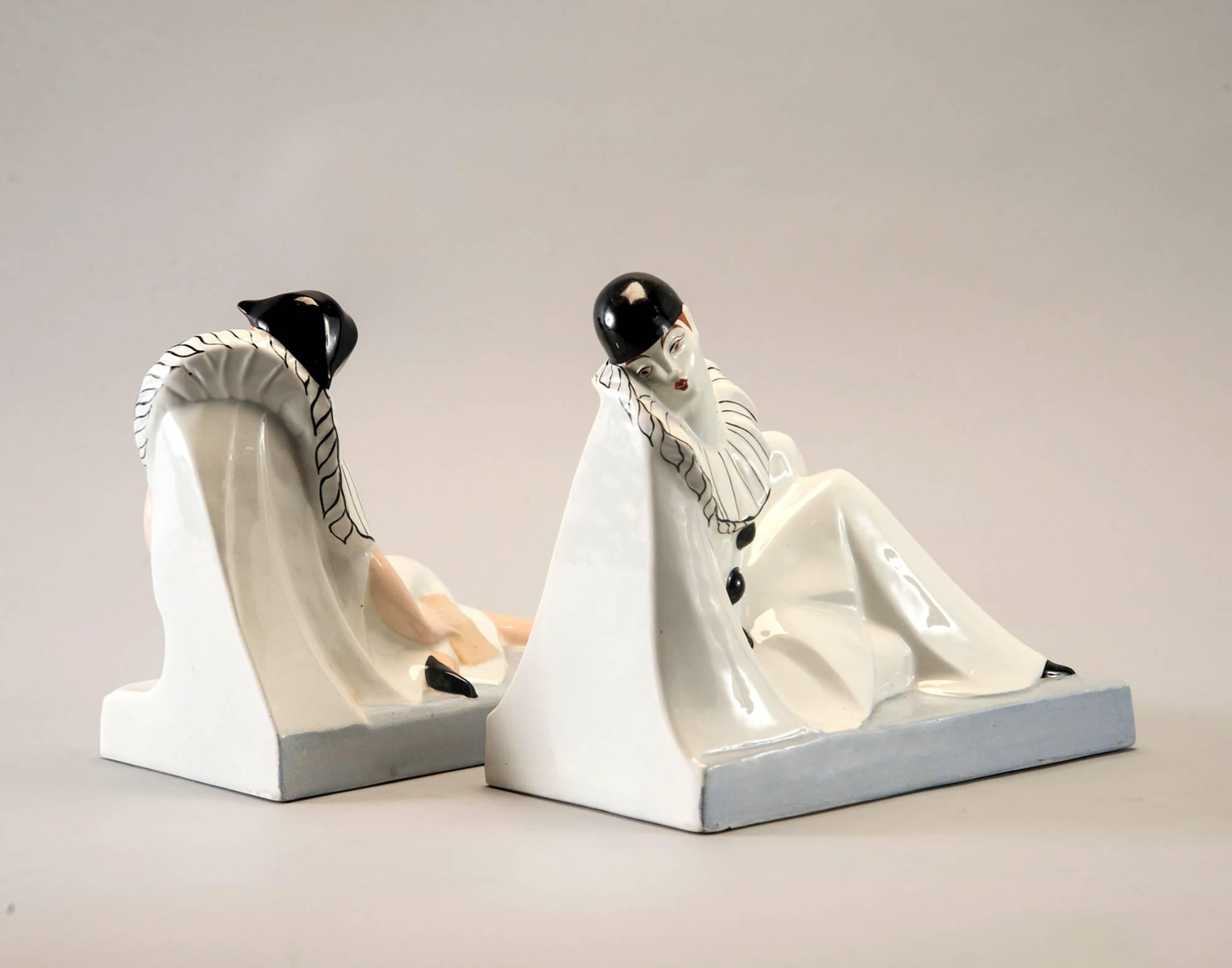 Pair of French porcelain bookends depict Pierrot and Columbine reclining figures, circa 1930s. Stamped Moulin Des Loups & Hamage Orchies France. Signed Genvane at side of base. Excellent vintage condition with no flaws found.
 